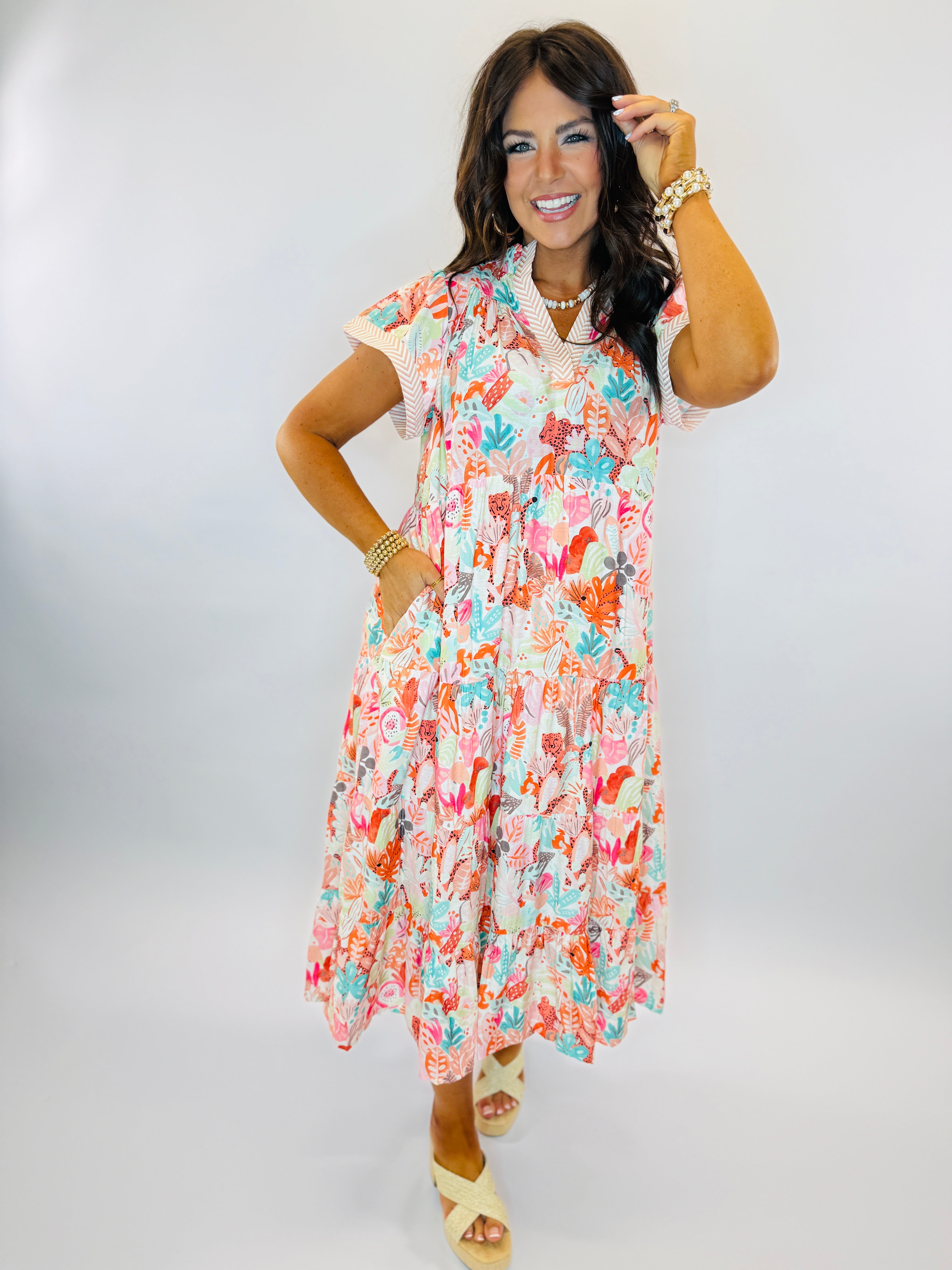 Woman wearing colorful floral Lexie dress with short sleeves and tiered midi-length skirt, styled with platform sandals.