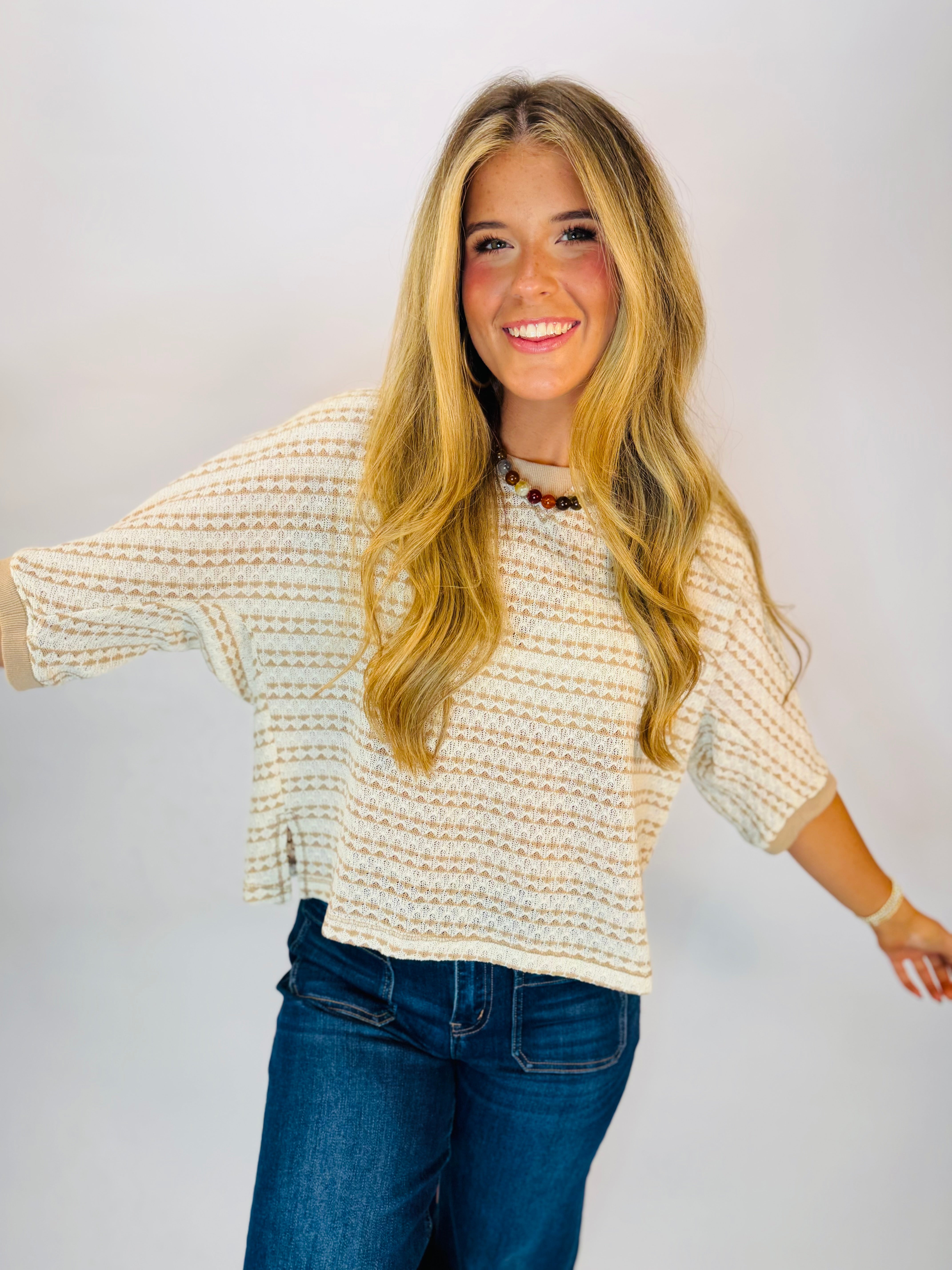 Cream and mocha striped open-knit sweater top with dolman sleeves, worn with dark jeans.
