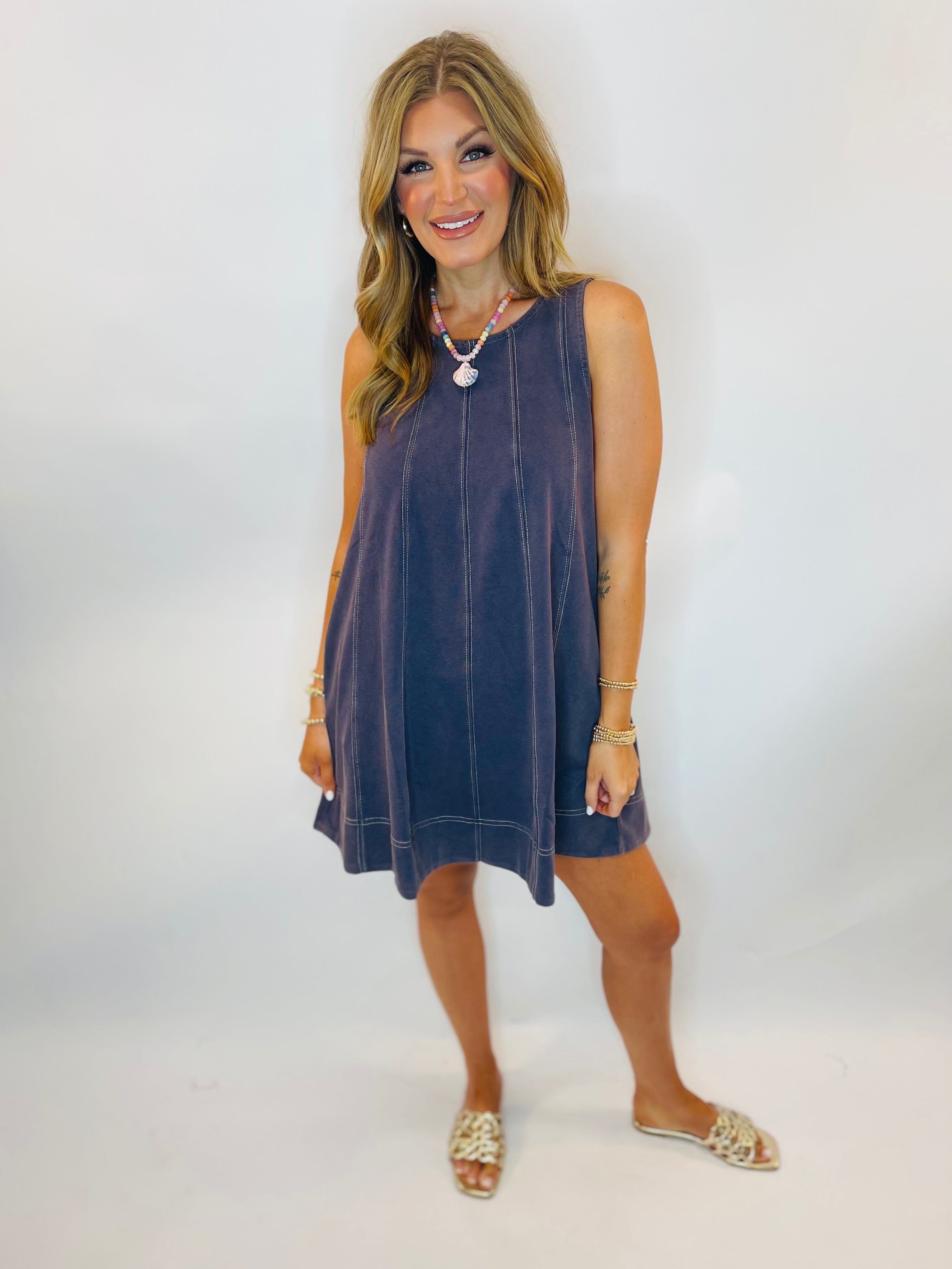 Navy sleeveless swing mini dress with contrast stitching, worn with sandals and shell necklace.