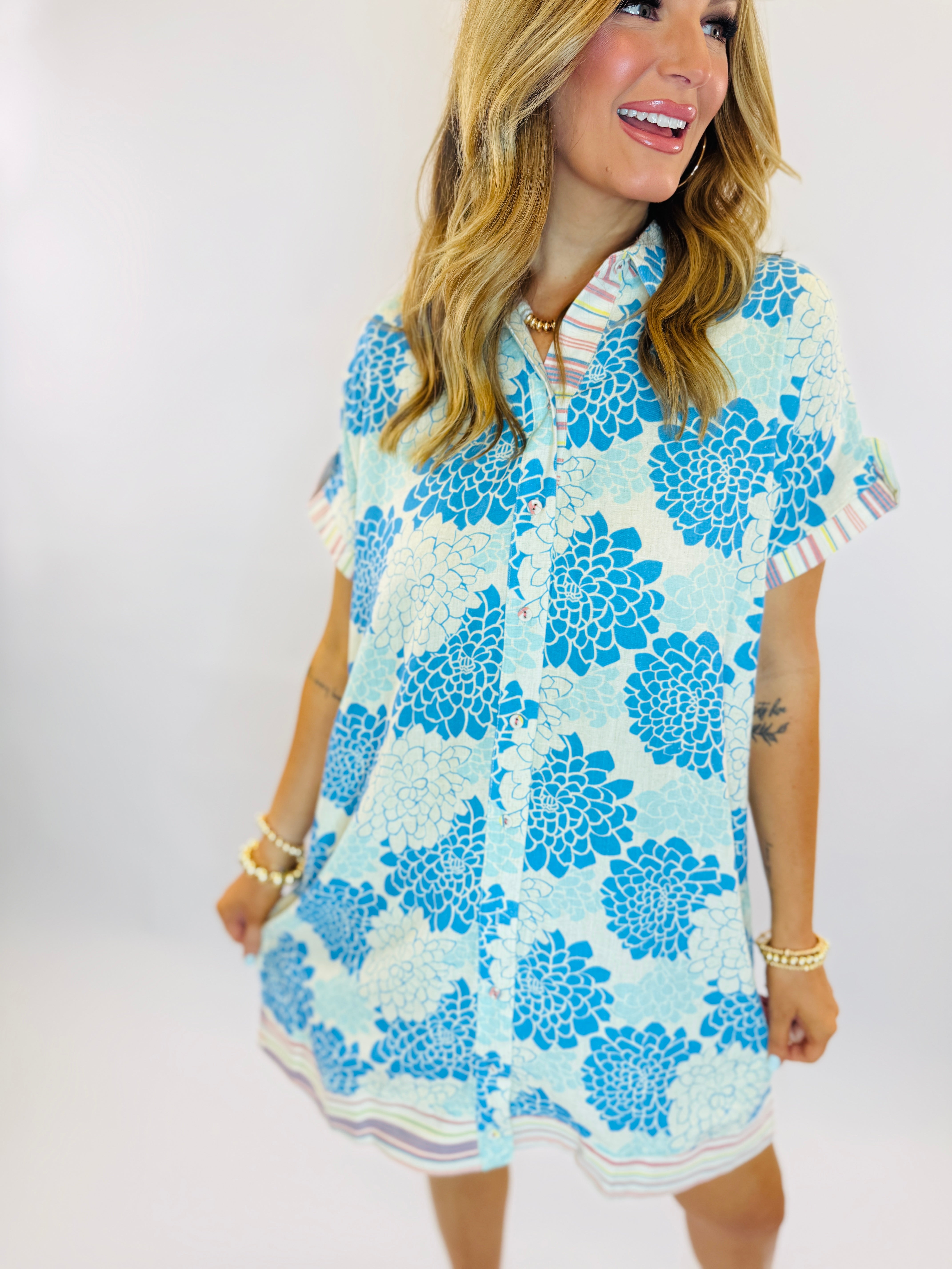 Woman wearing blue and white floral print Rachel dress with short sleeves and button-front design