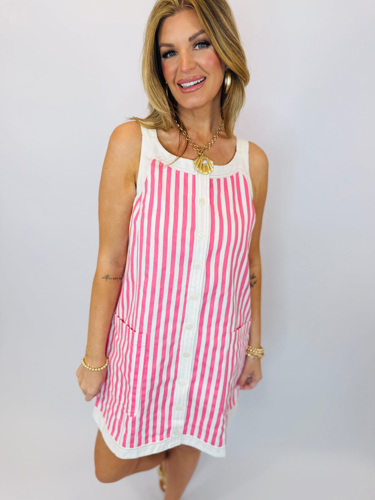 Woman wearing pink and white striped sleeveless mini dress with button front and white collar trim