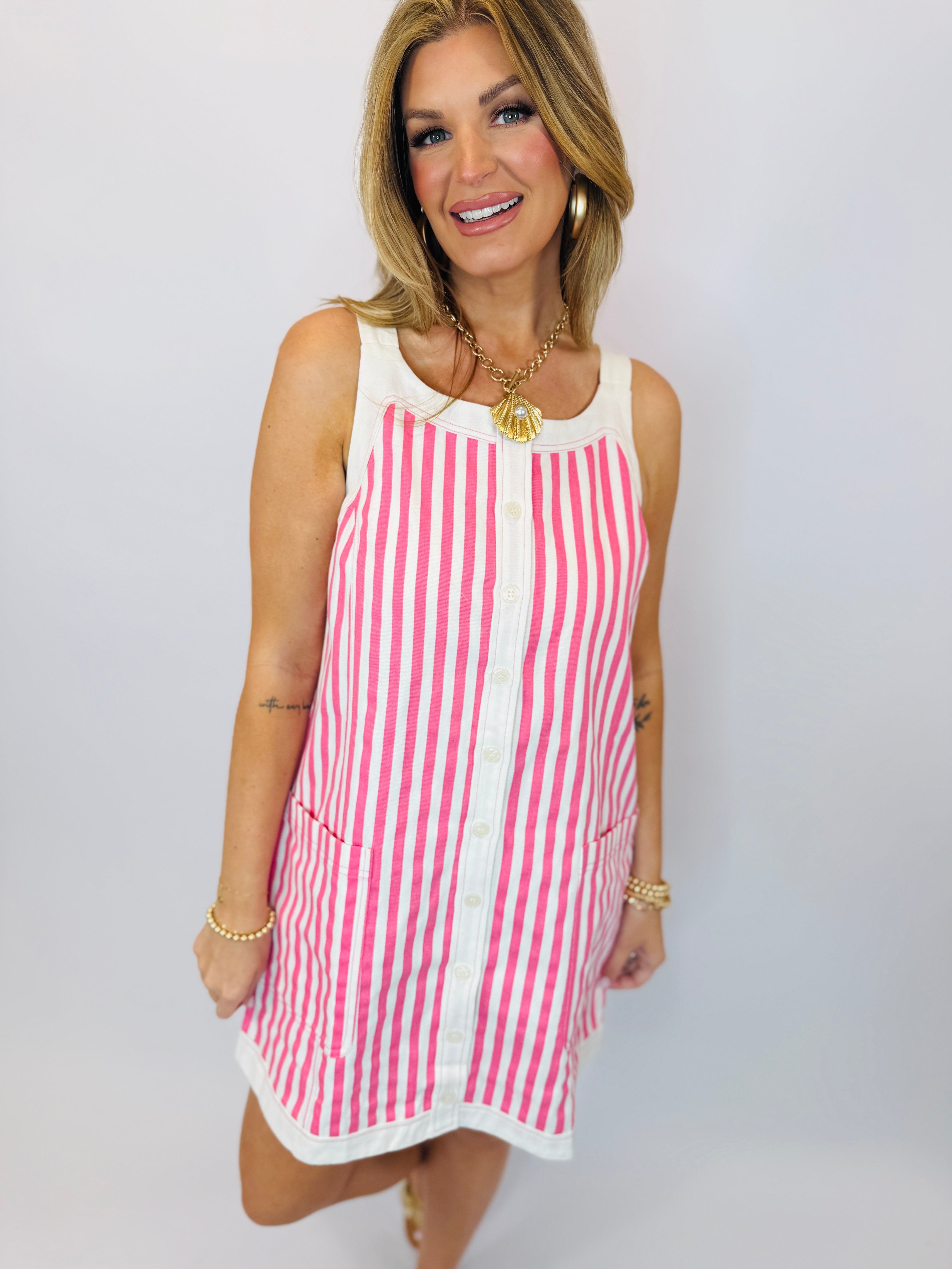 Woman wearing pink and white striped sleeveless mini dress with button front and white collar trim