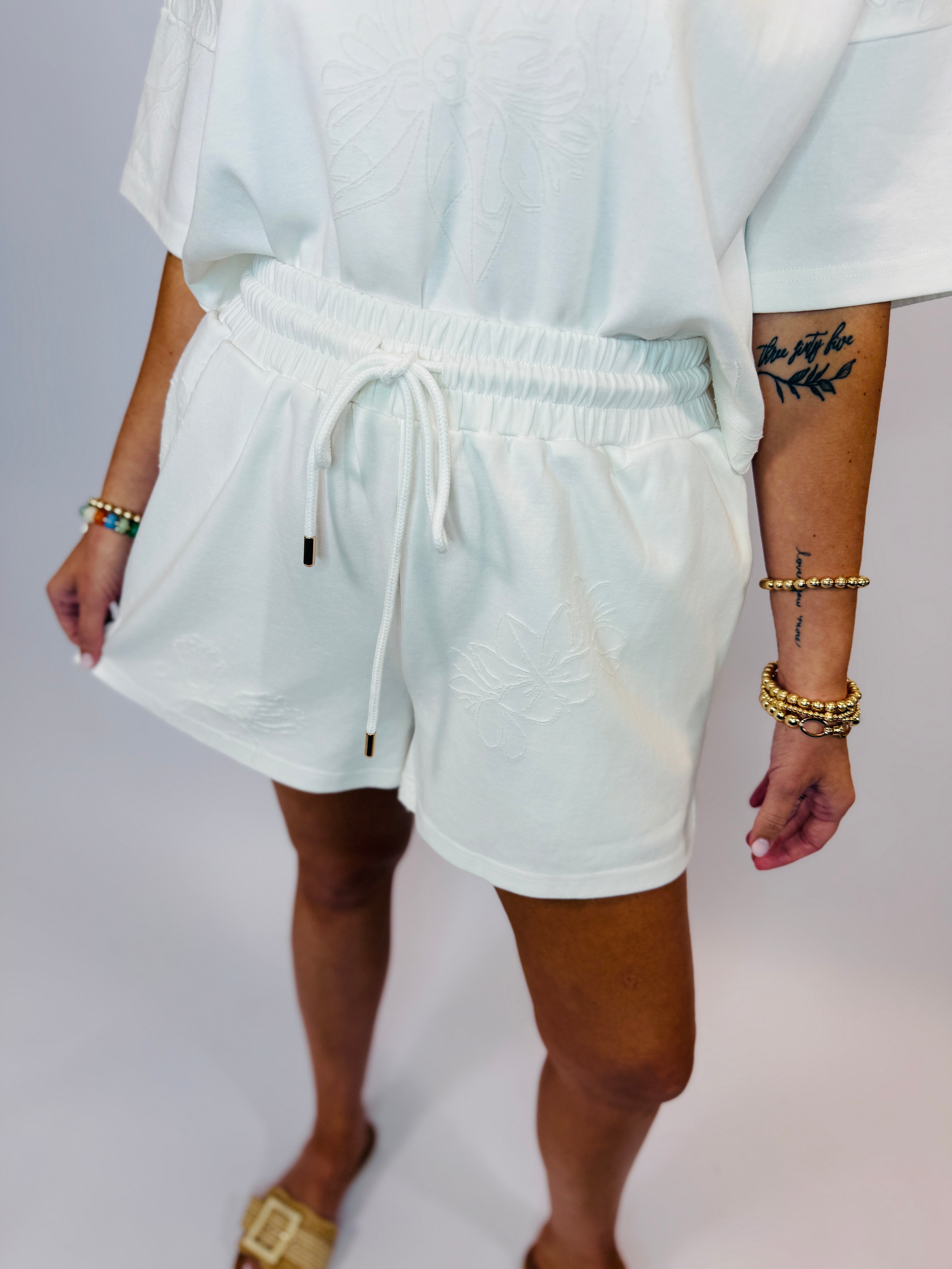 Woman wearing light mint green matching top and shorts set with drawstring waist and embroidered details