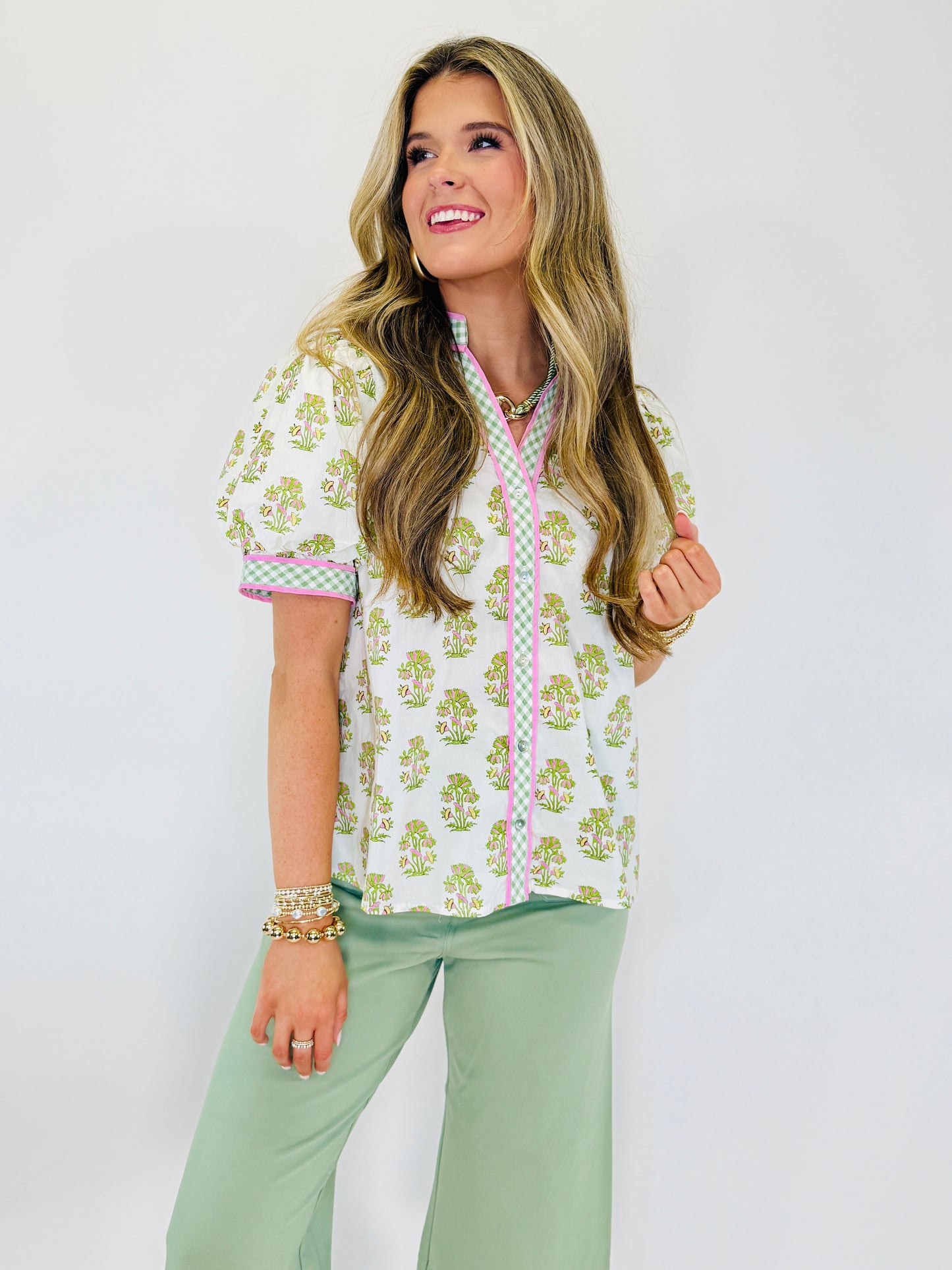 Woman wearing Peyton soft knit top with green floral print, pink gingham trim, and mint green pants.