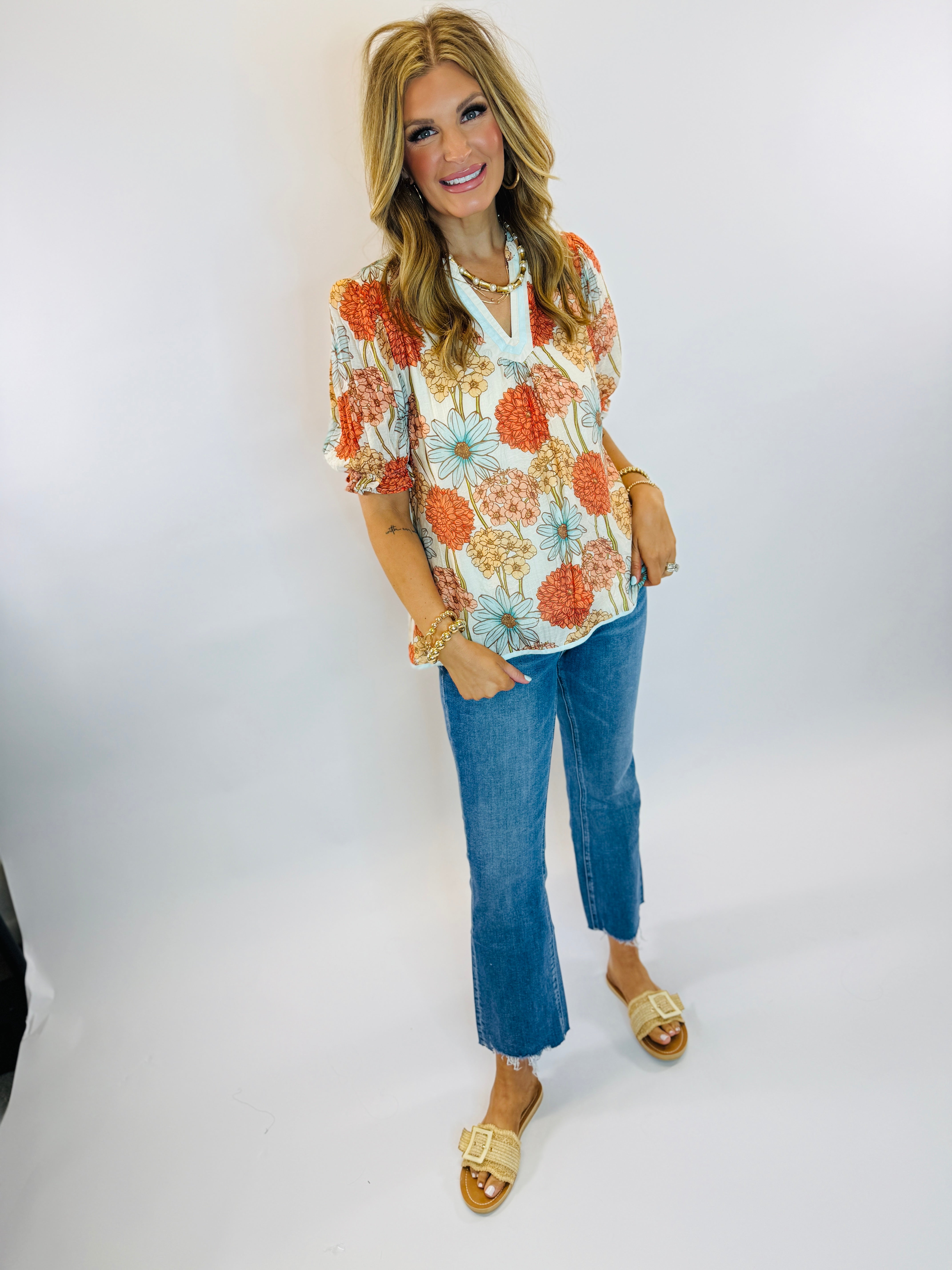 Woman wearing floral print blouse and cropped blue Jenna jeans with frayed hem and gold sandals