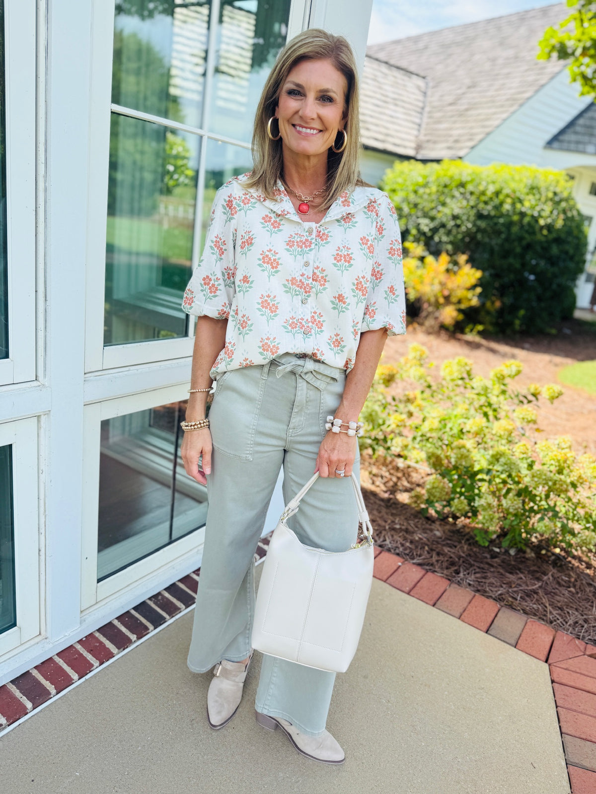 Allie cream multi V neck floral top styled with sage green wide leg pants, neutral ankle boots, and a cream handbag.