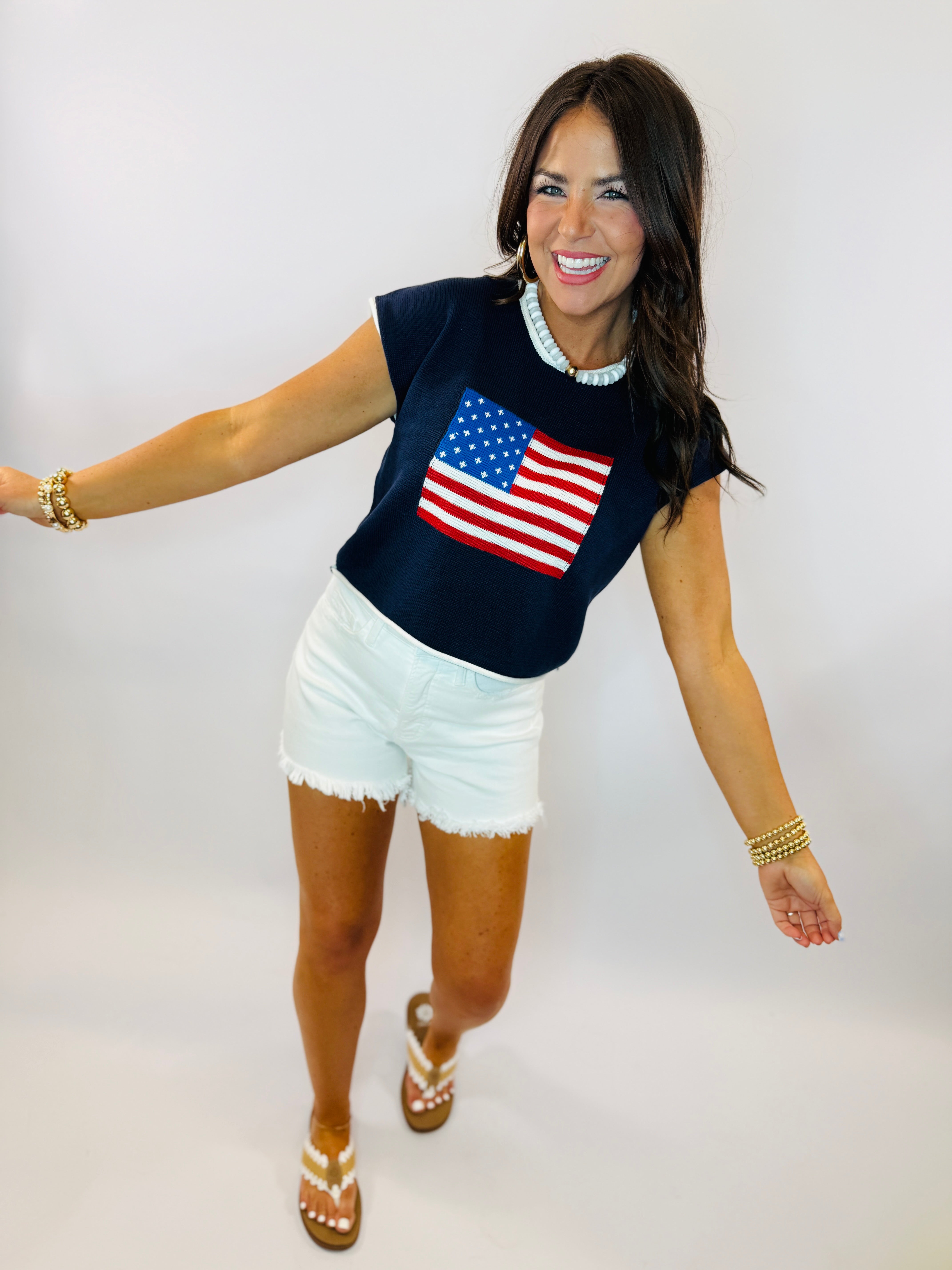 Woman wearing navy blue Sydney top with American flag design, white shorts, and pearl necklace