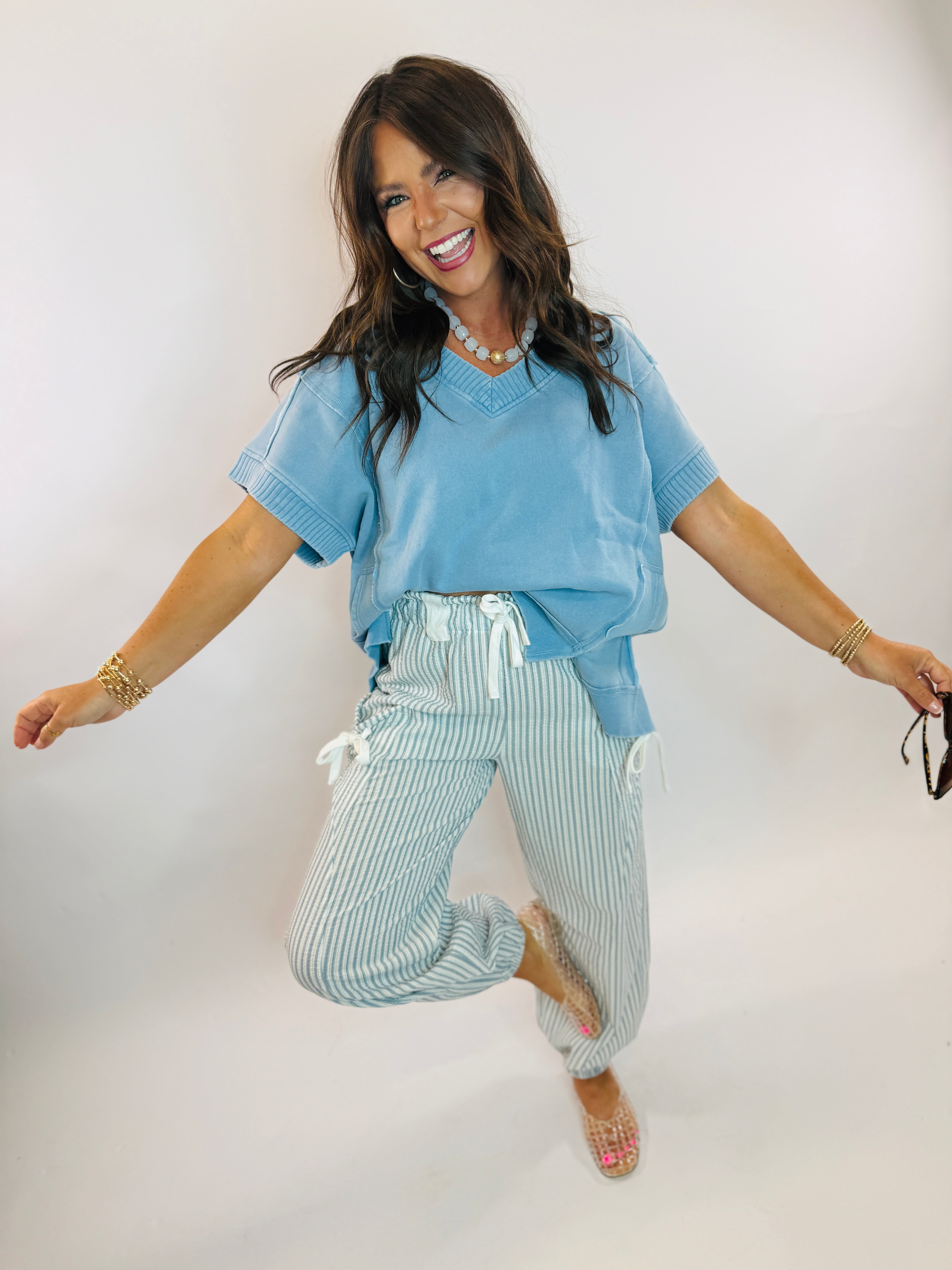 Woman wearing a light blue oversized V-neck short-sleeve top with ribbed trim details.