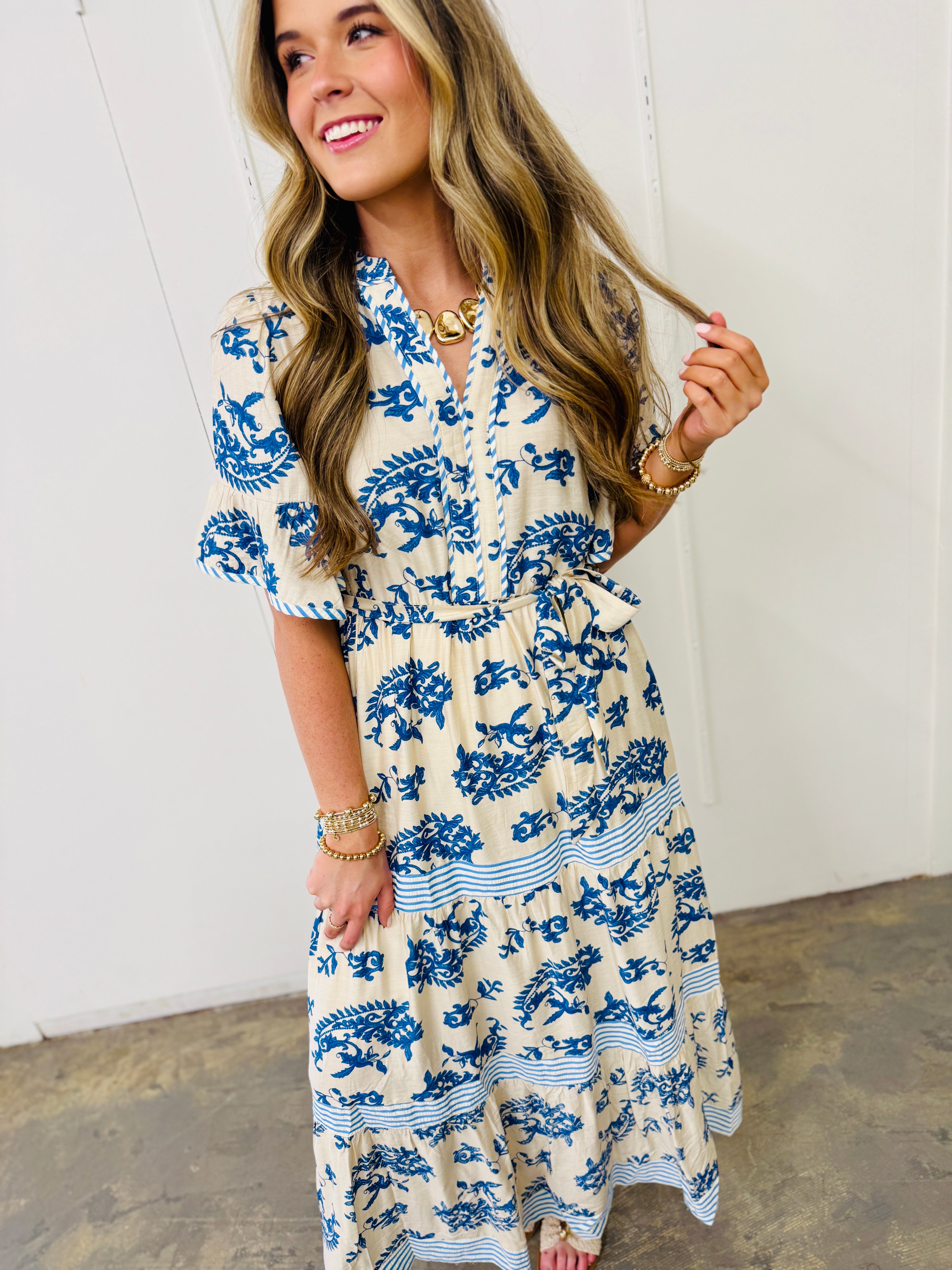 Woman wearing blue and white floral Barrett dress with tie waist and short sleeves