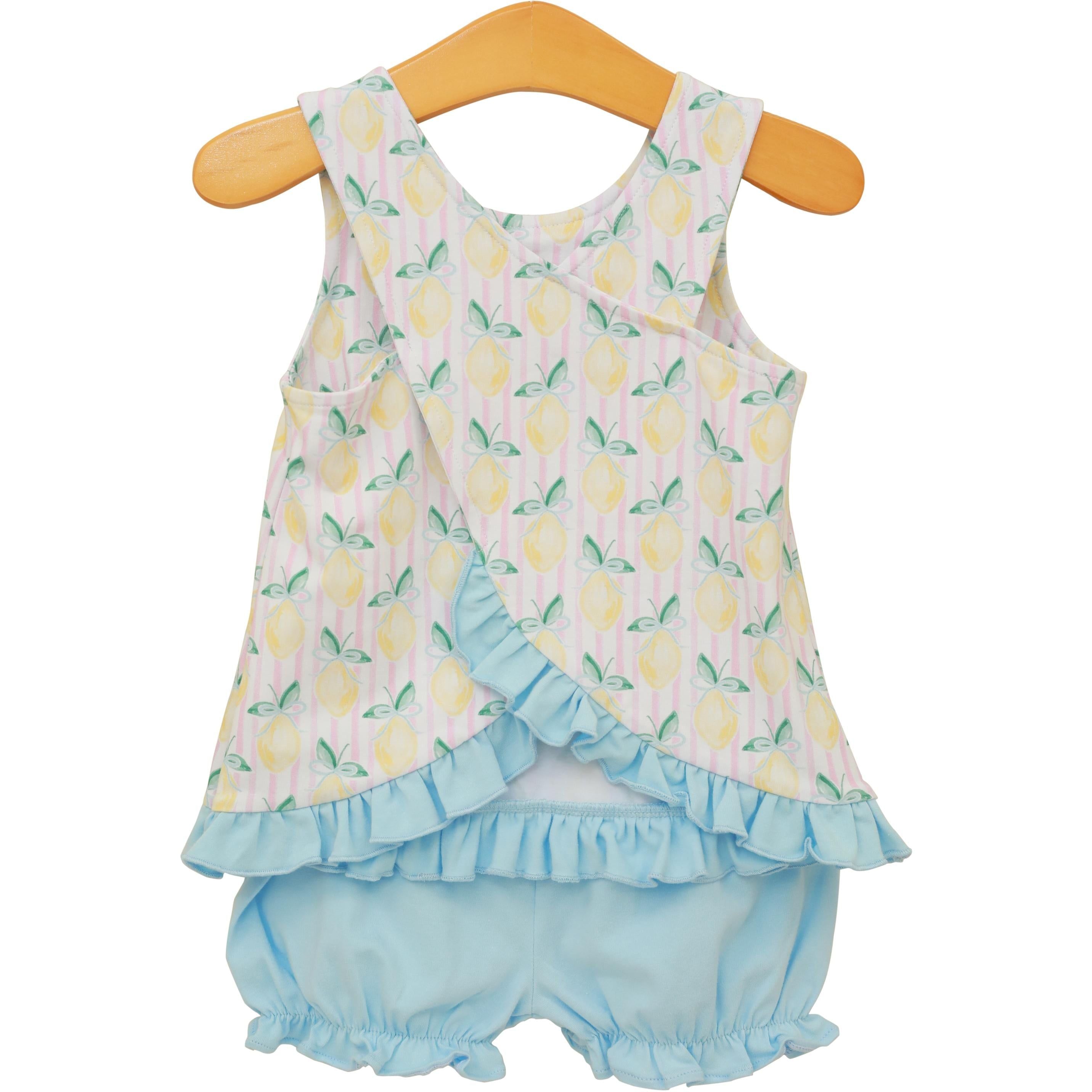 Baby girl two-piece outfit with lemon print sleeveless top and light blue ruffled bloomers on wooden hanger.