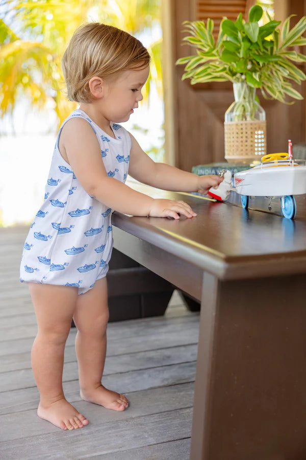 Toddler in blue whale print bubble romper playing with toy airplane on wooden table