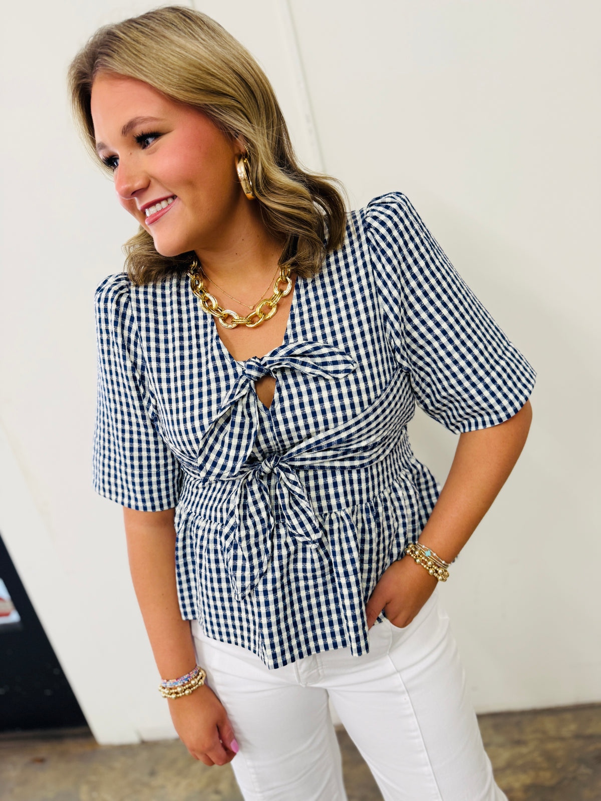 Woman wearing blue and white gingham checkered top with tie front detail and short sleeves