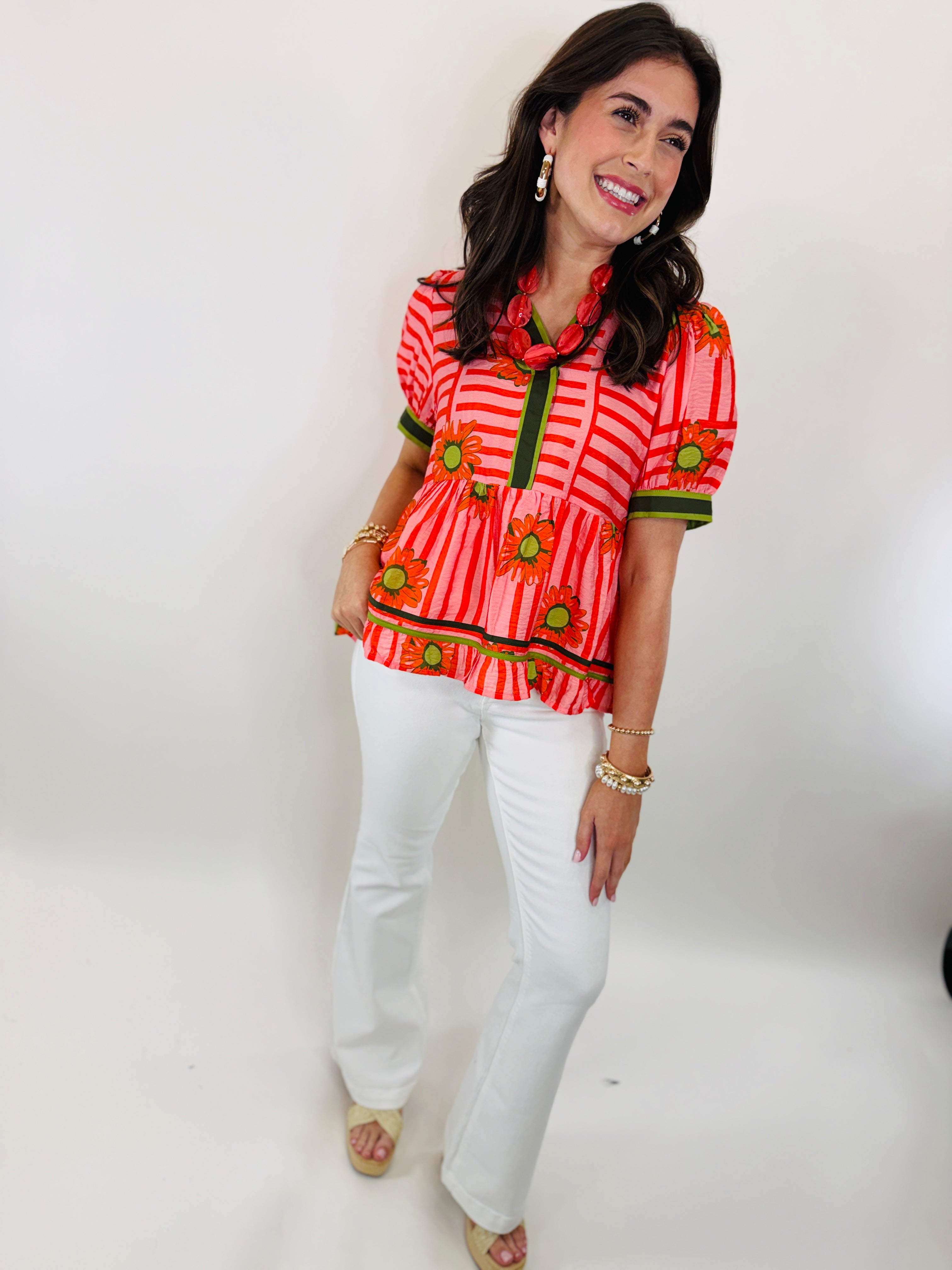 Woman wearing red and pink striped floral Billie top with white pants and gold jewelry