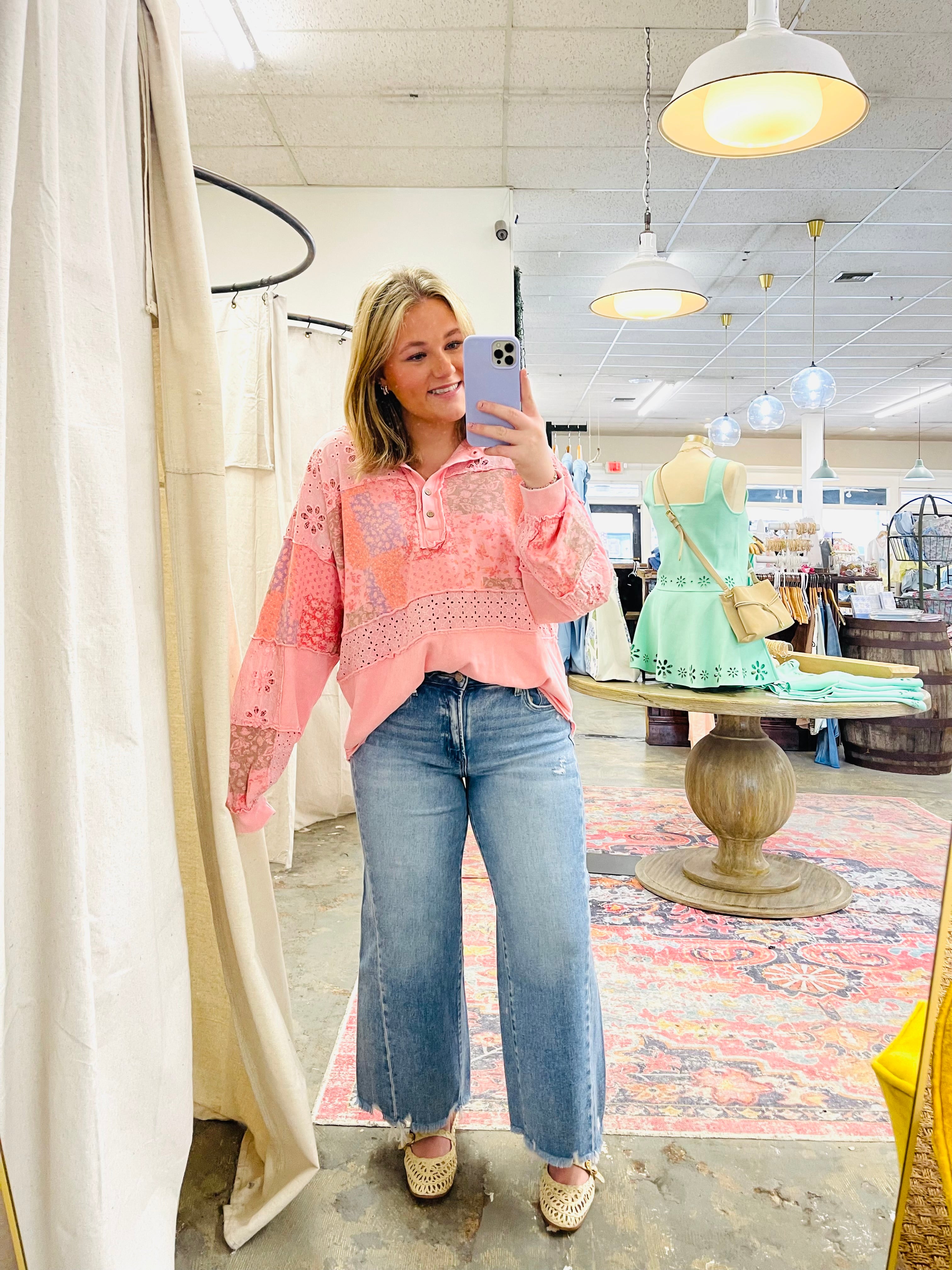 Woman wearing pink eyelet lace Finley Everyday Top with wide-leg jeans in clothing store dressing room