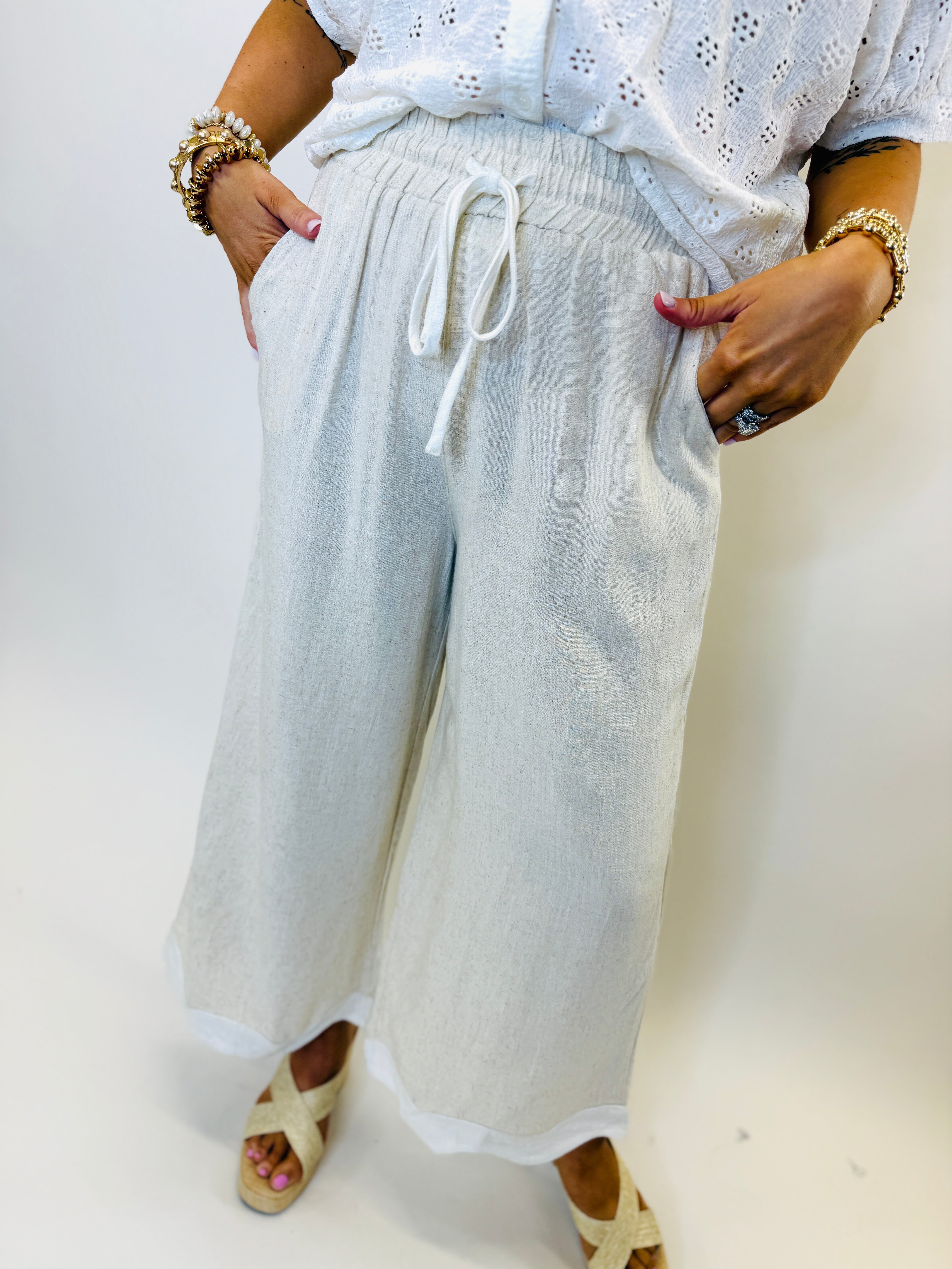 Light blue linen drawstring pants with elastic waistband and wide-leg silhouette, styled with white sandals