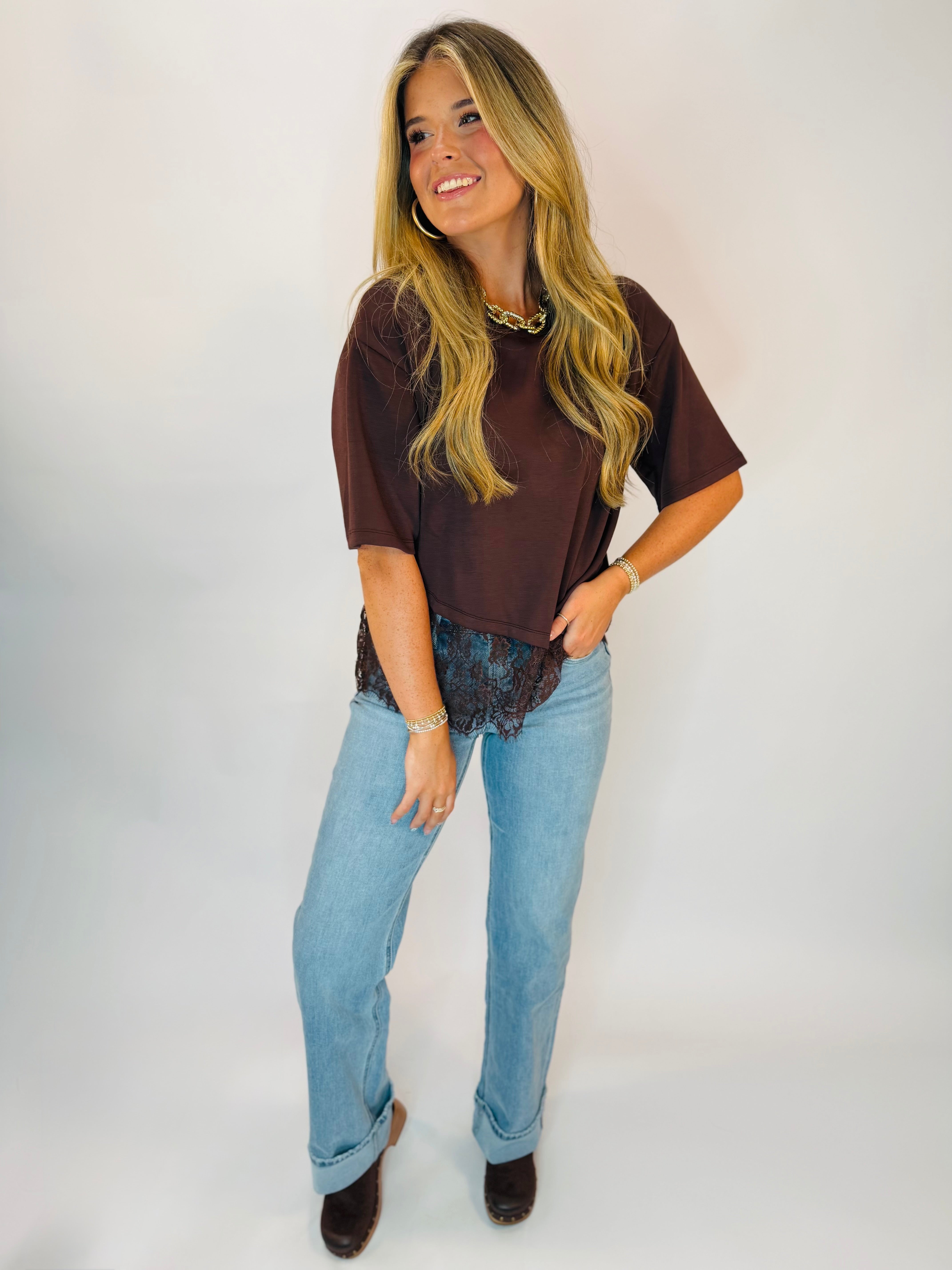 Brown cropped tee with lace hem detail, paired with light wash straight-leg jeans and brown boots.