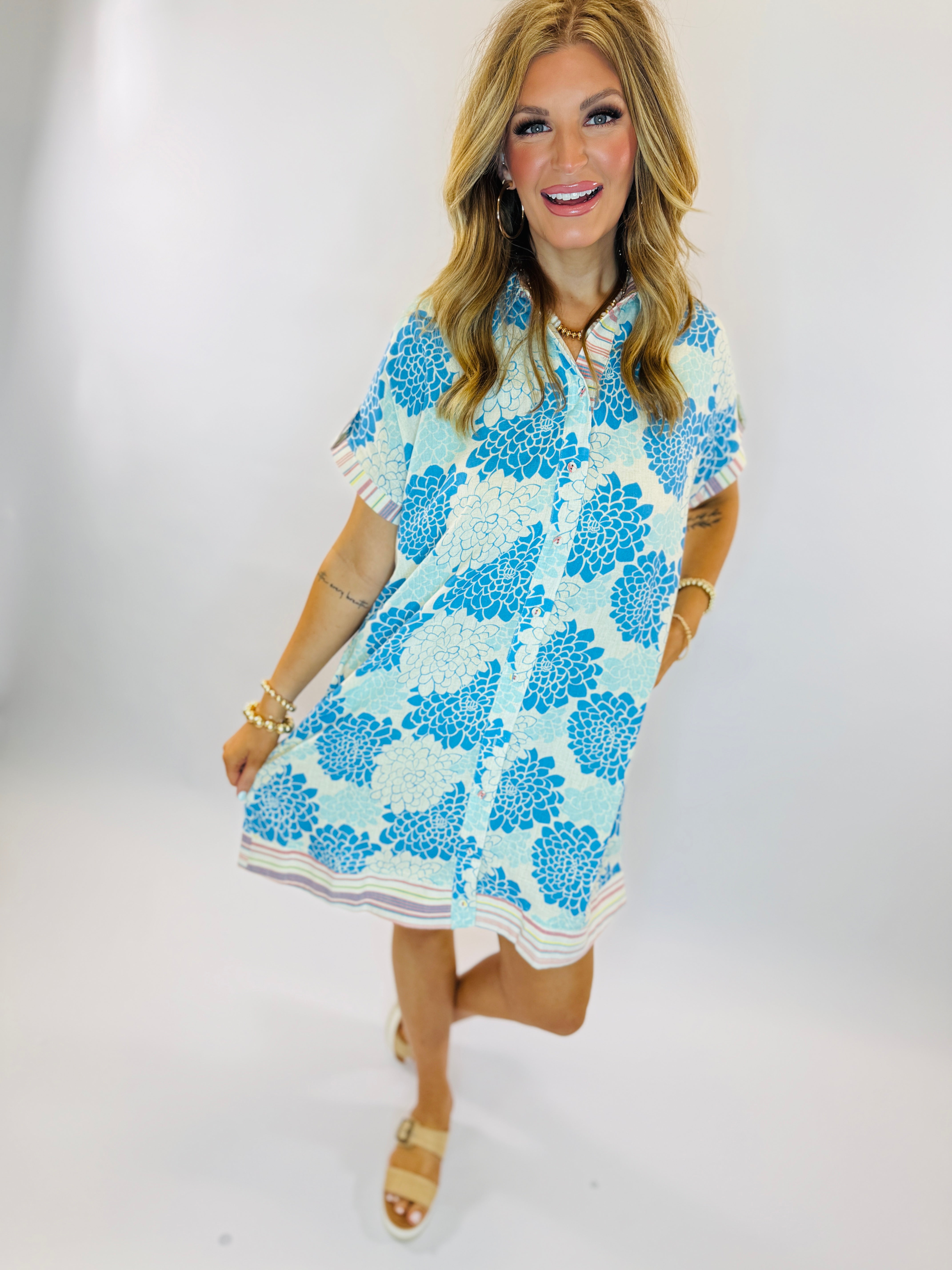 Woman wearing blue and white floral Rachel dress with short sleeves and striped hem detail.
