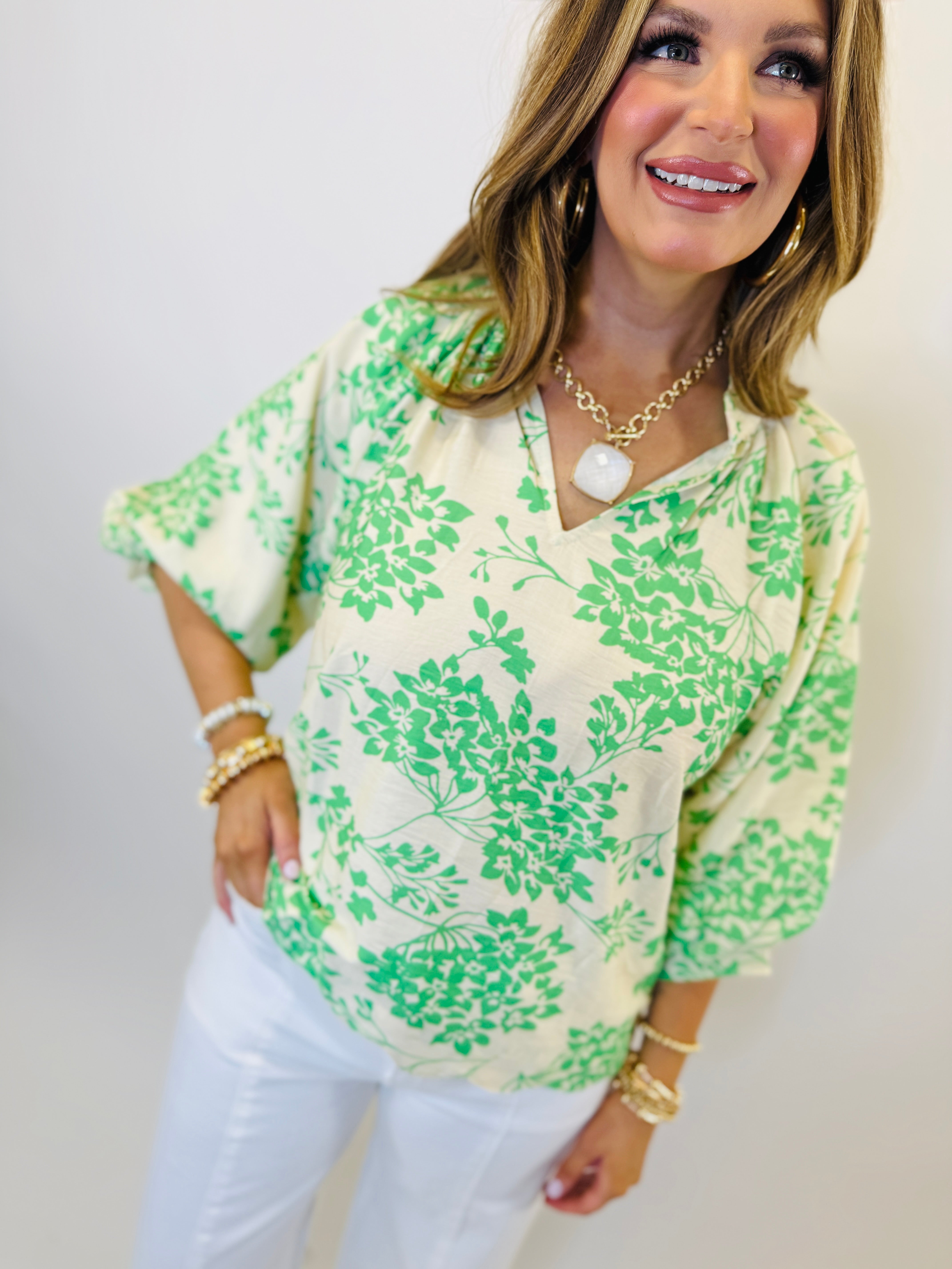 Woman wearing white and green floral print Amelia top with three-quarter sleeves and v-neck collar.