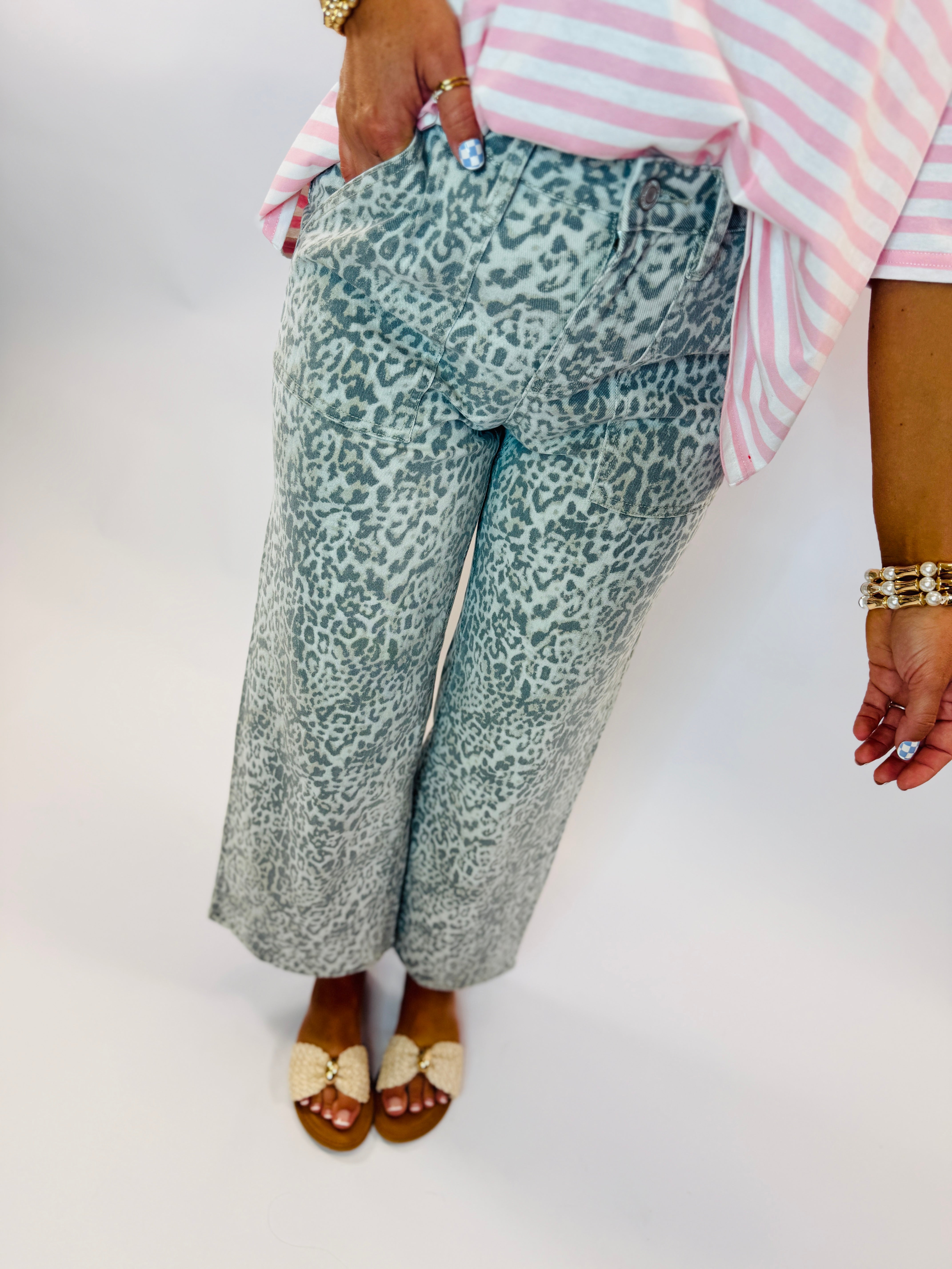 Woman wearing green leopard print wide-leg cropped denim jeans with pink striped top and woven sandals