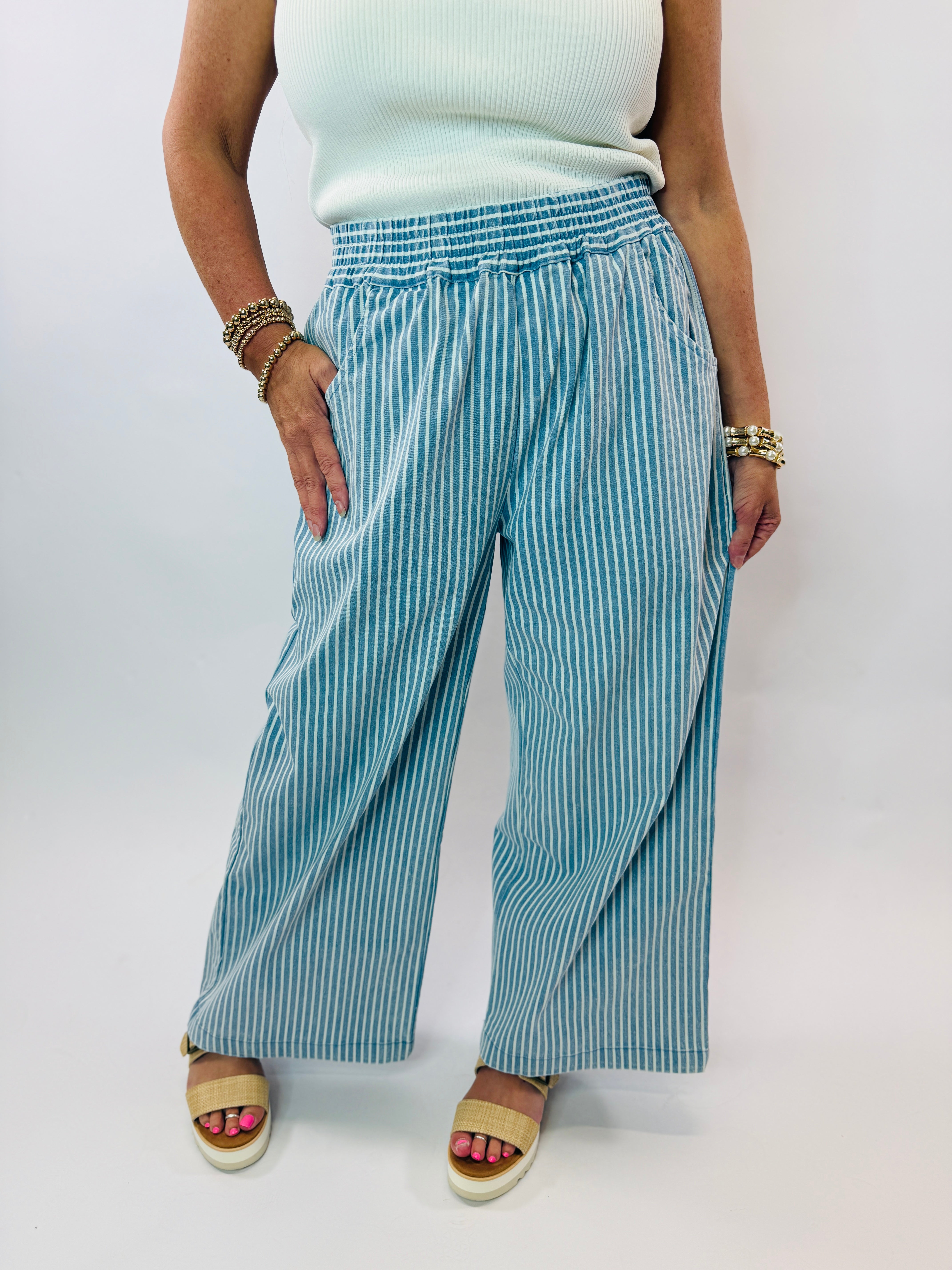 Woman wearing blue and white striped wide leg pants with elastic waistband and platform sandals