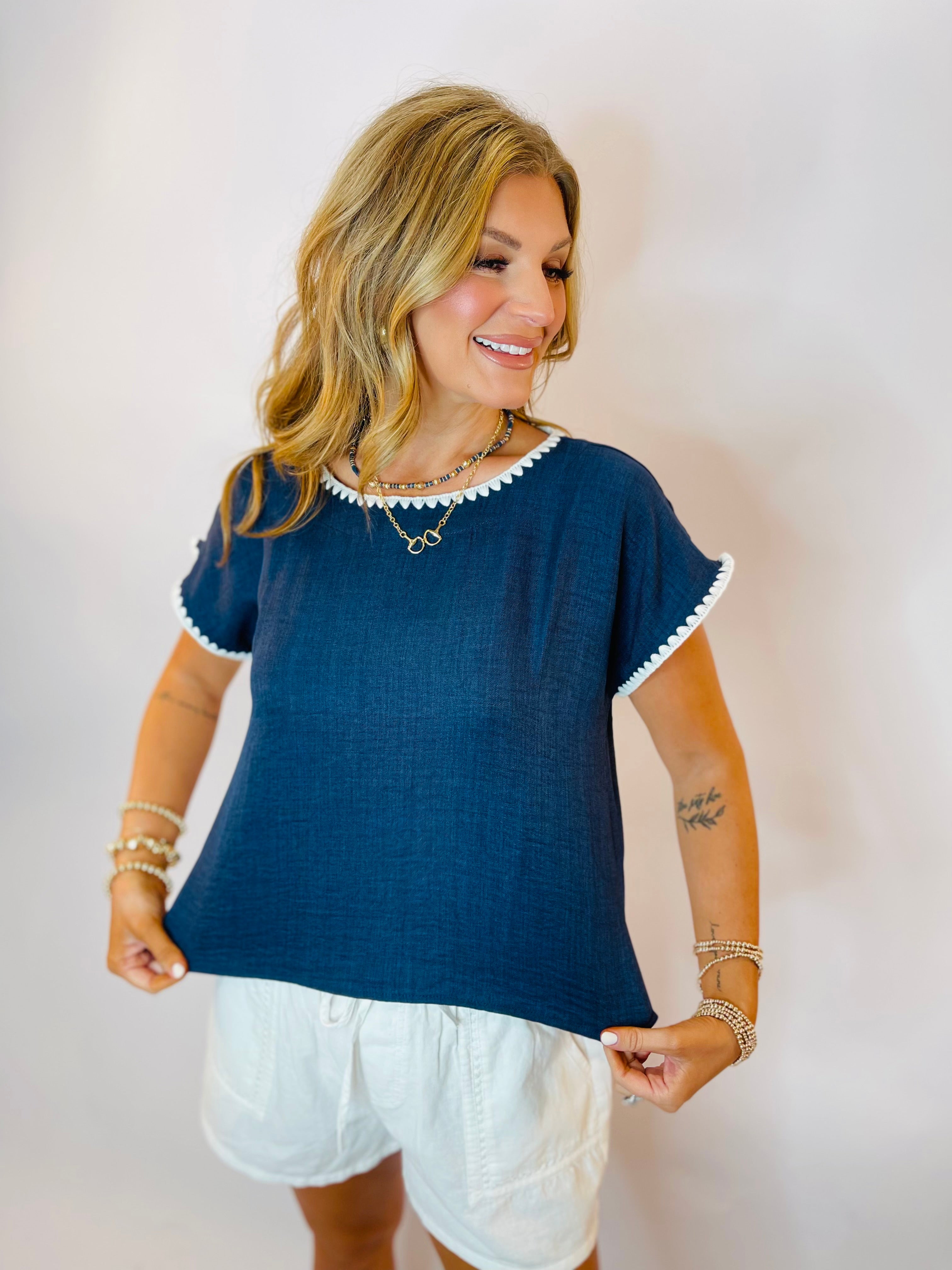 Navy blue linen short-sleeve top with white scallop trim detailing at neckline and sleeves.