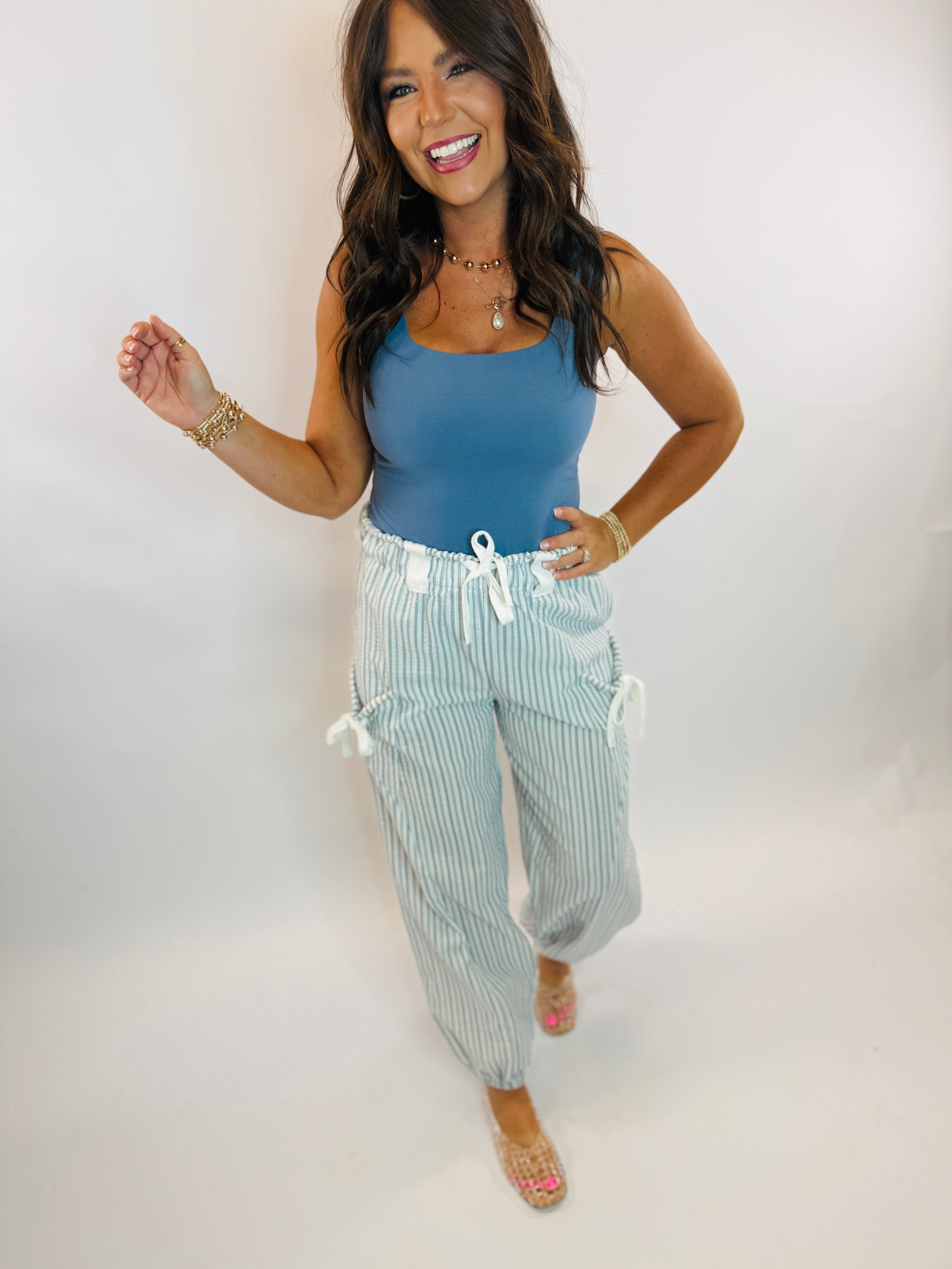 Woman wearing light blue and white striped drawstring cargo pants with a blue bodysuit top.