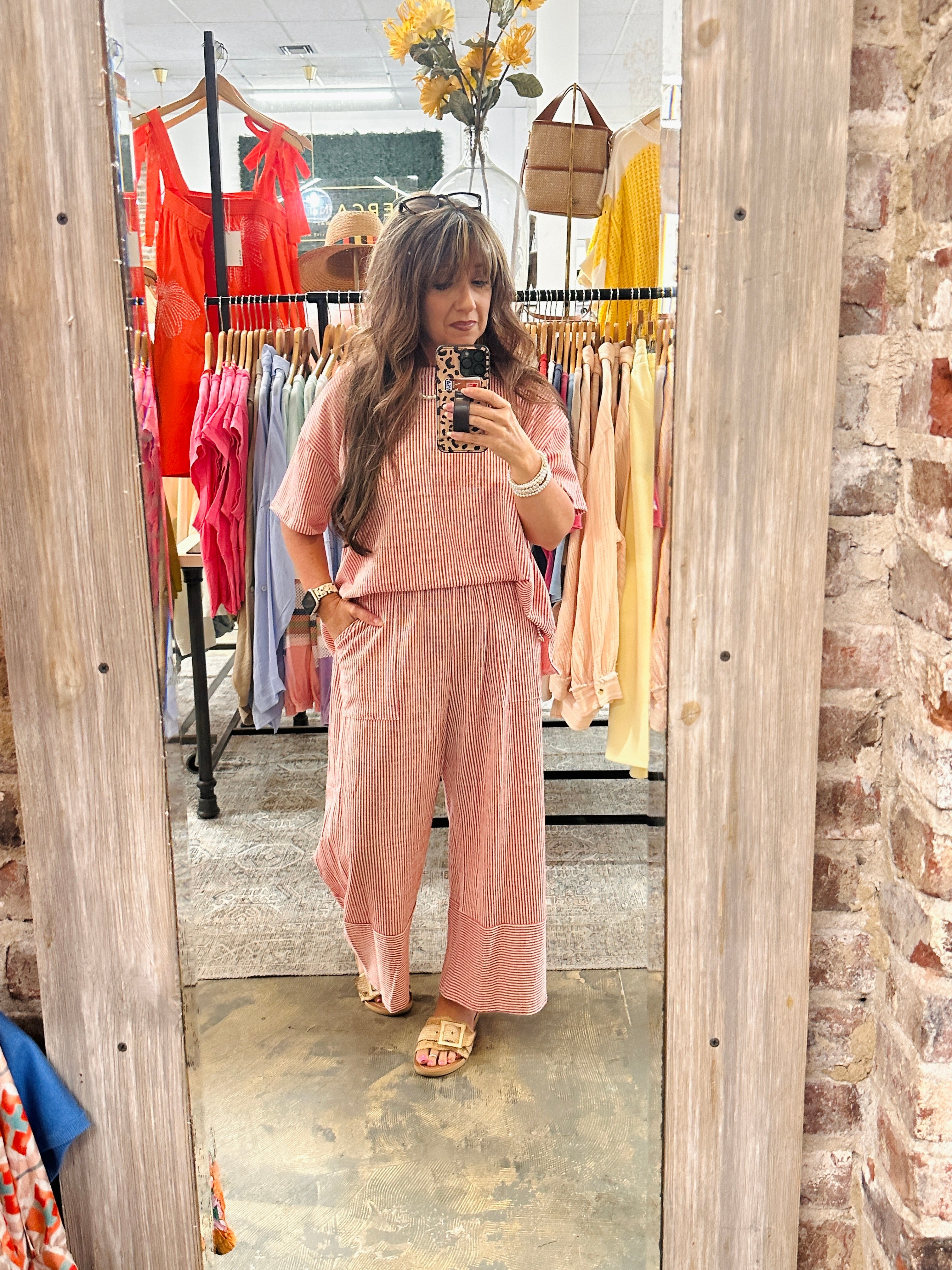 Woman wearing pink striped two-piece Ava Set with short-sleeve top and wide-leg pants in clothing store mirror