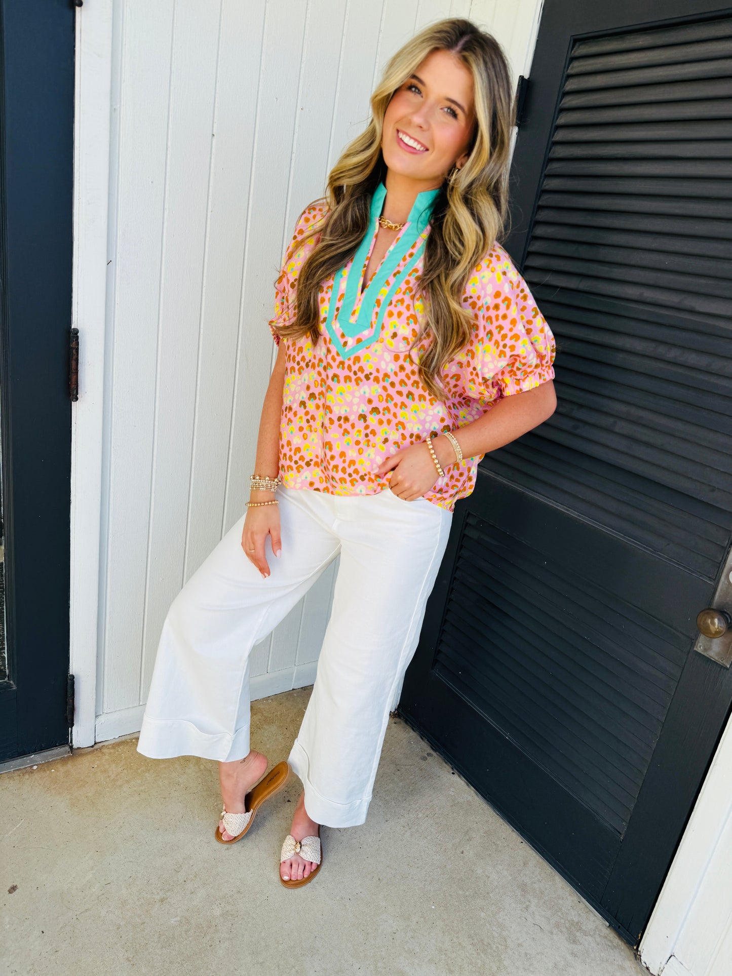 Woman wearing colorful polka dot Leila Sunday Soft Top with turquoise trim and white pants