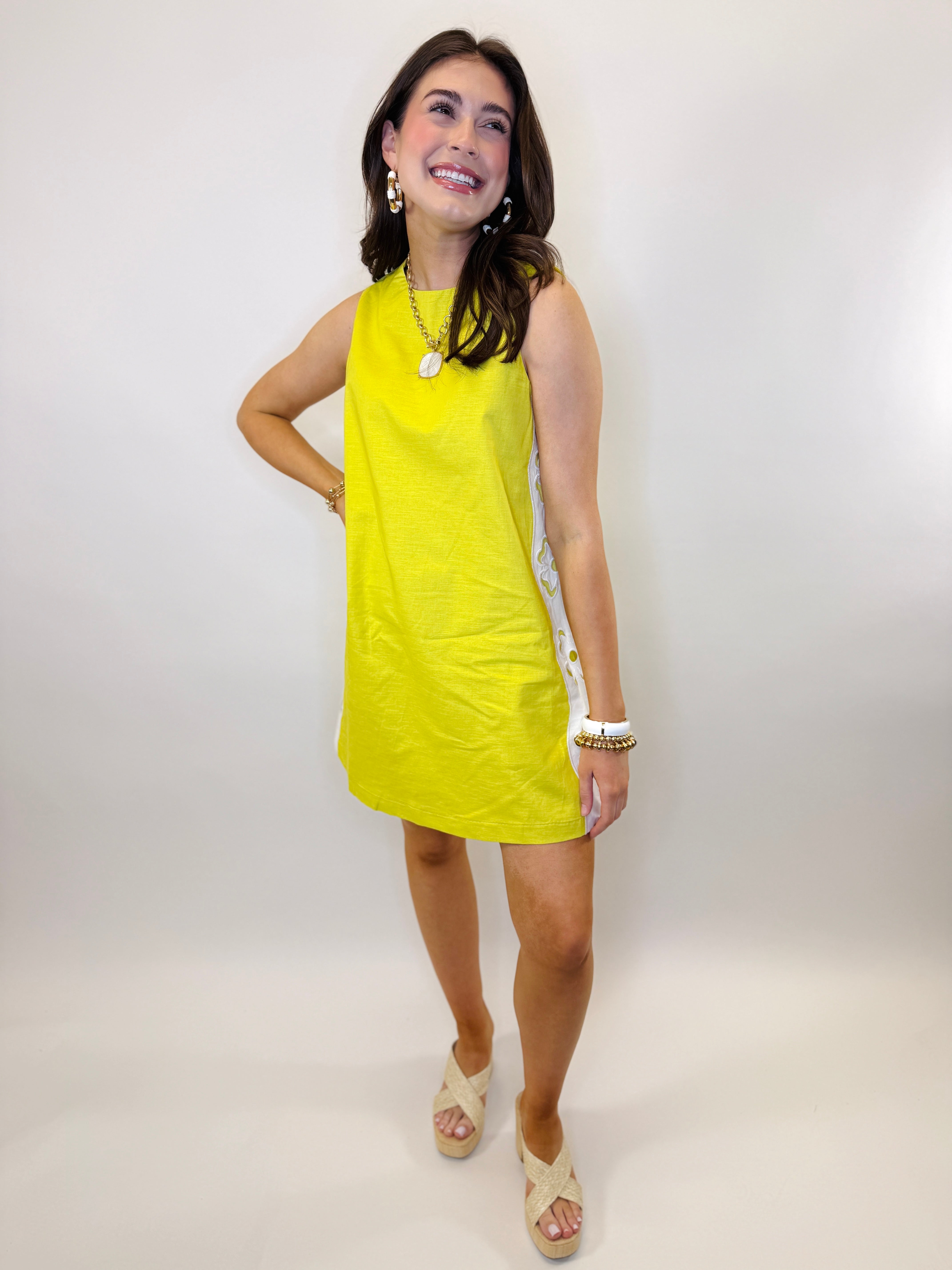 Woman wearing bright yellow sleeveless Farrah dress with white decorative side trim and platform sandals