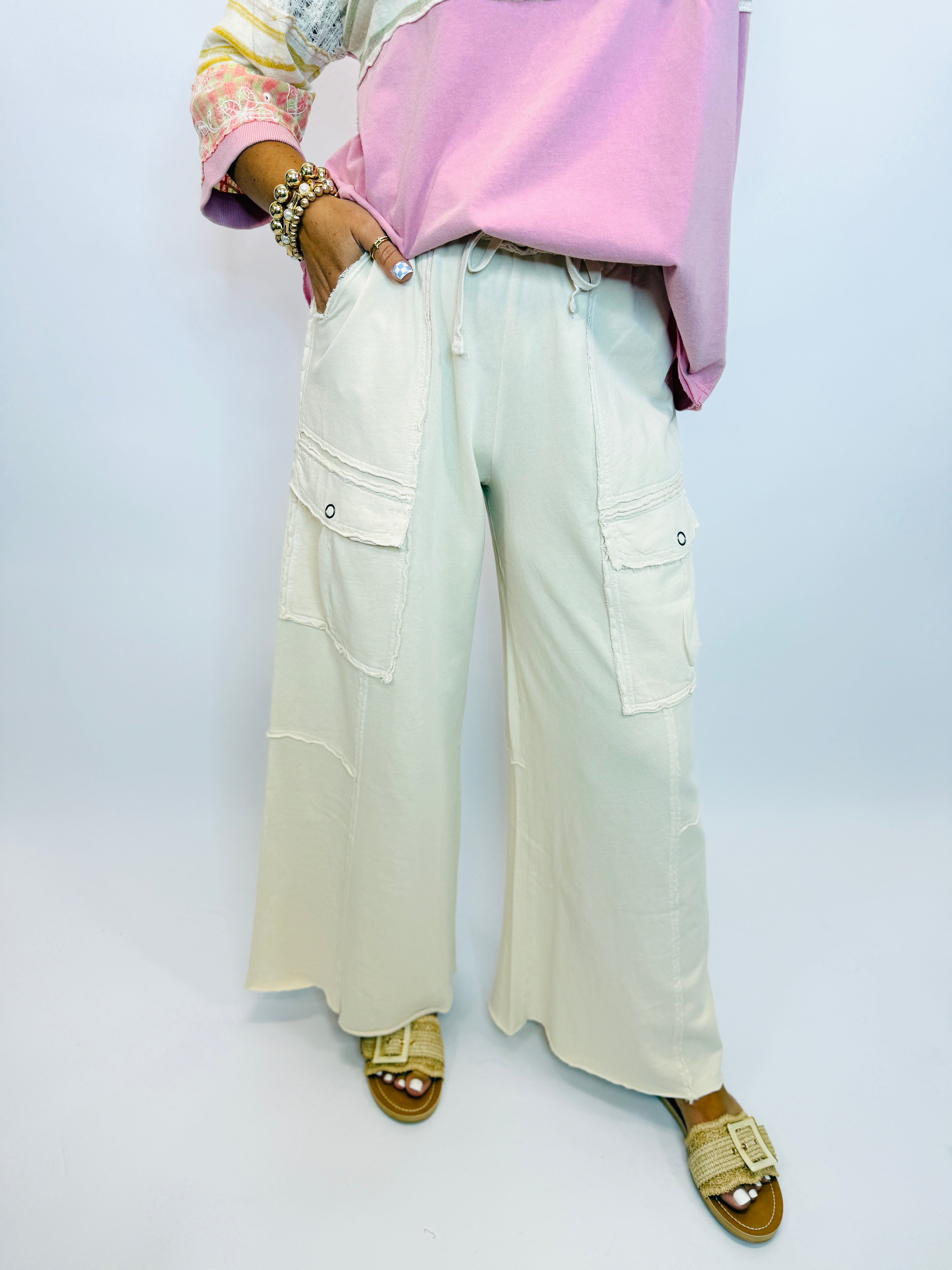 Light green wide-leg cargo pants with side pockets and drawstring waist, styled with pink top and gold sandals.