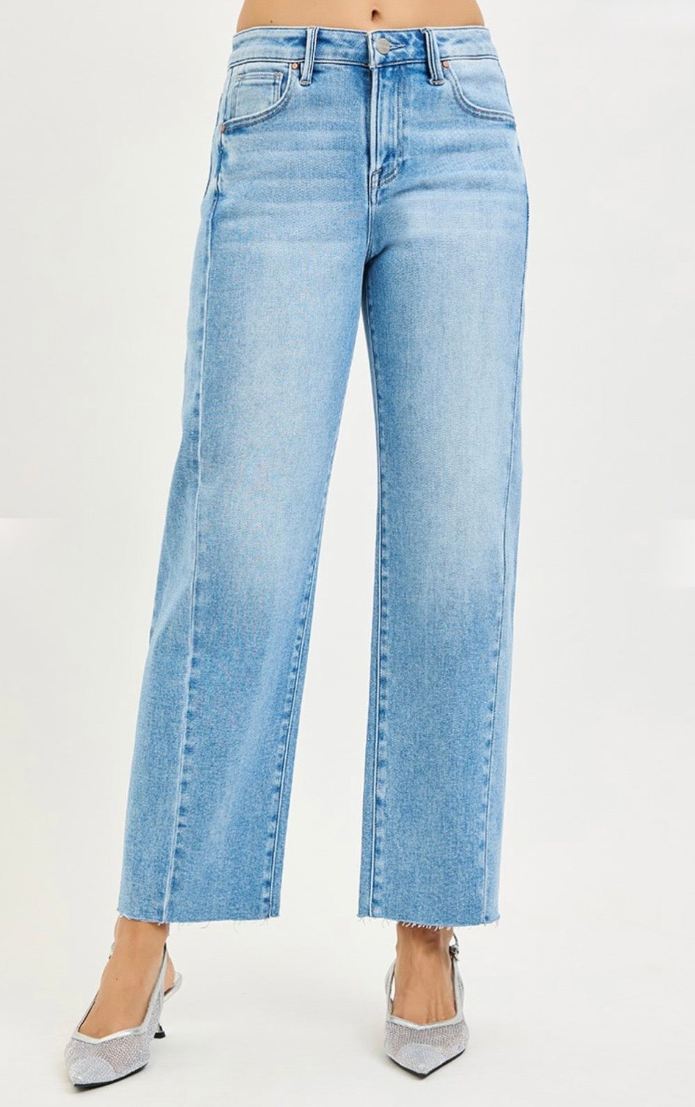 Light blue high-waisted barrel jeans with raw hem worn with silver pointed-toe heels