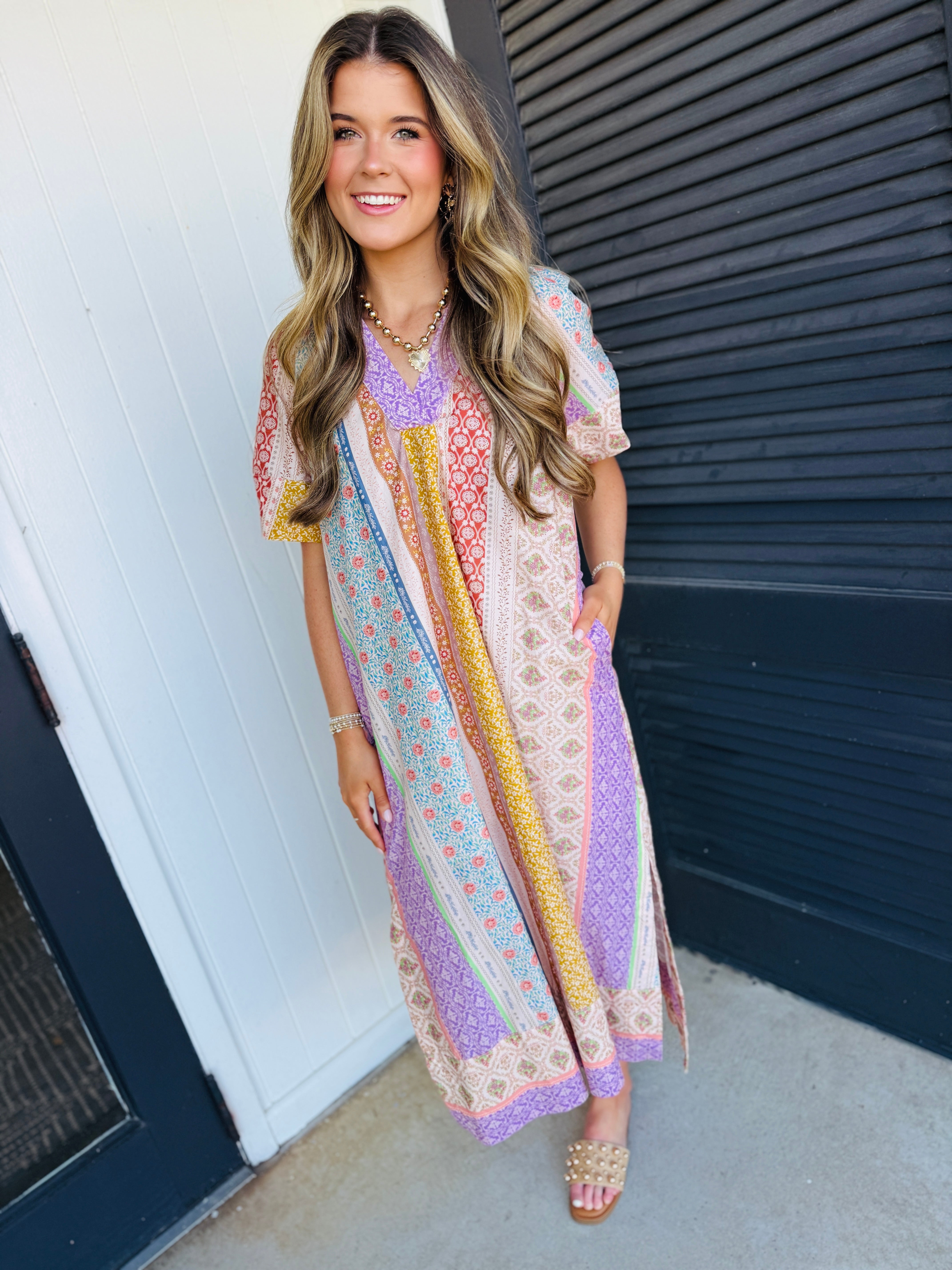 Woman wearing colorful patchwork midi dress with mixed patterns in purple, yellow, and floral prints