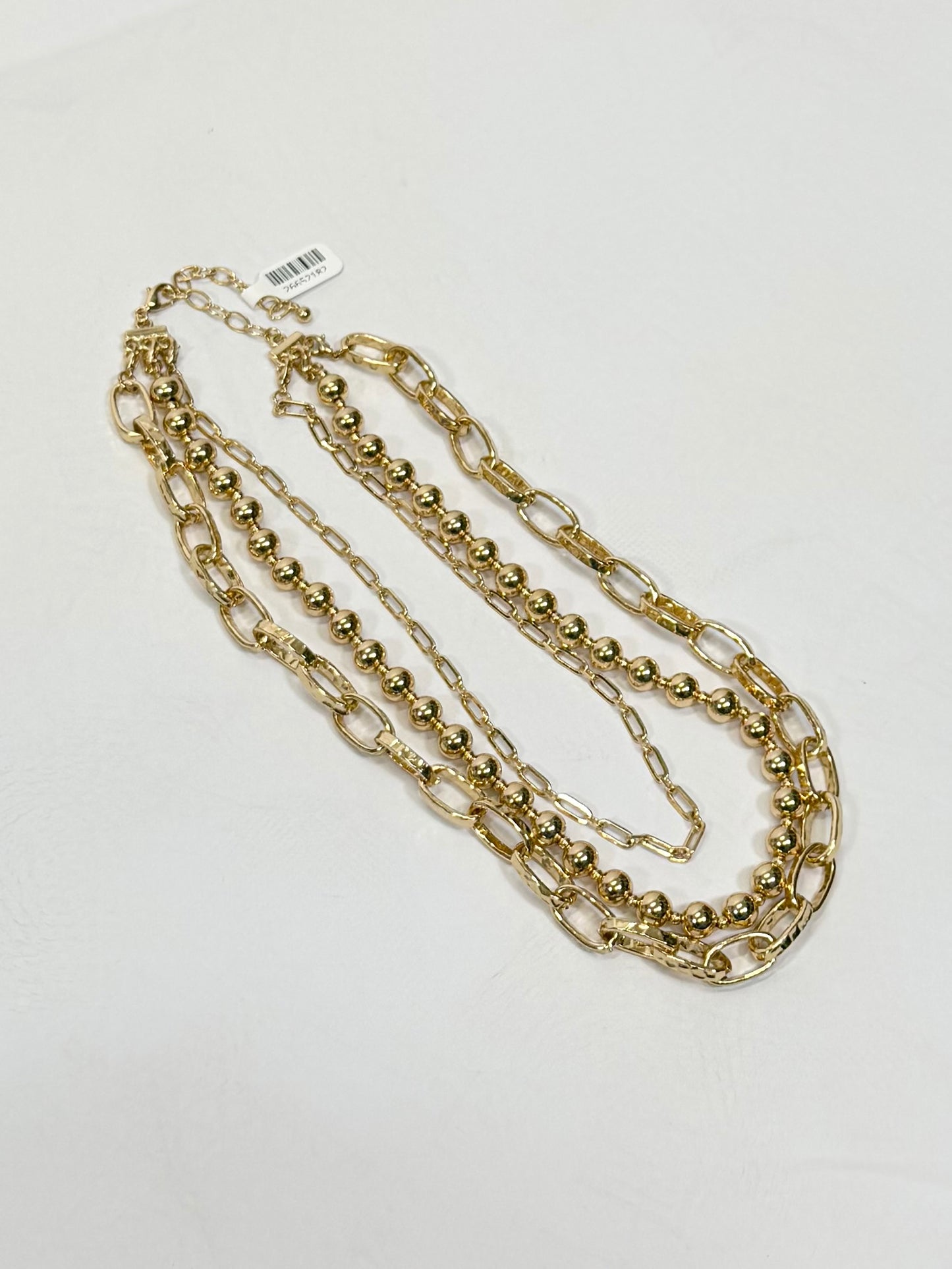 Gold three-layered necklace set featuring ball beads and oval link chains with lobster clasp closure.