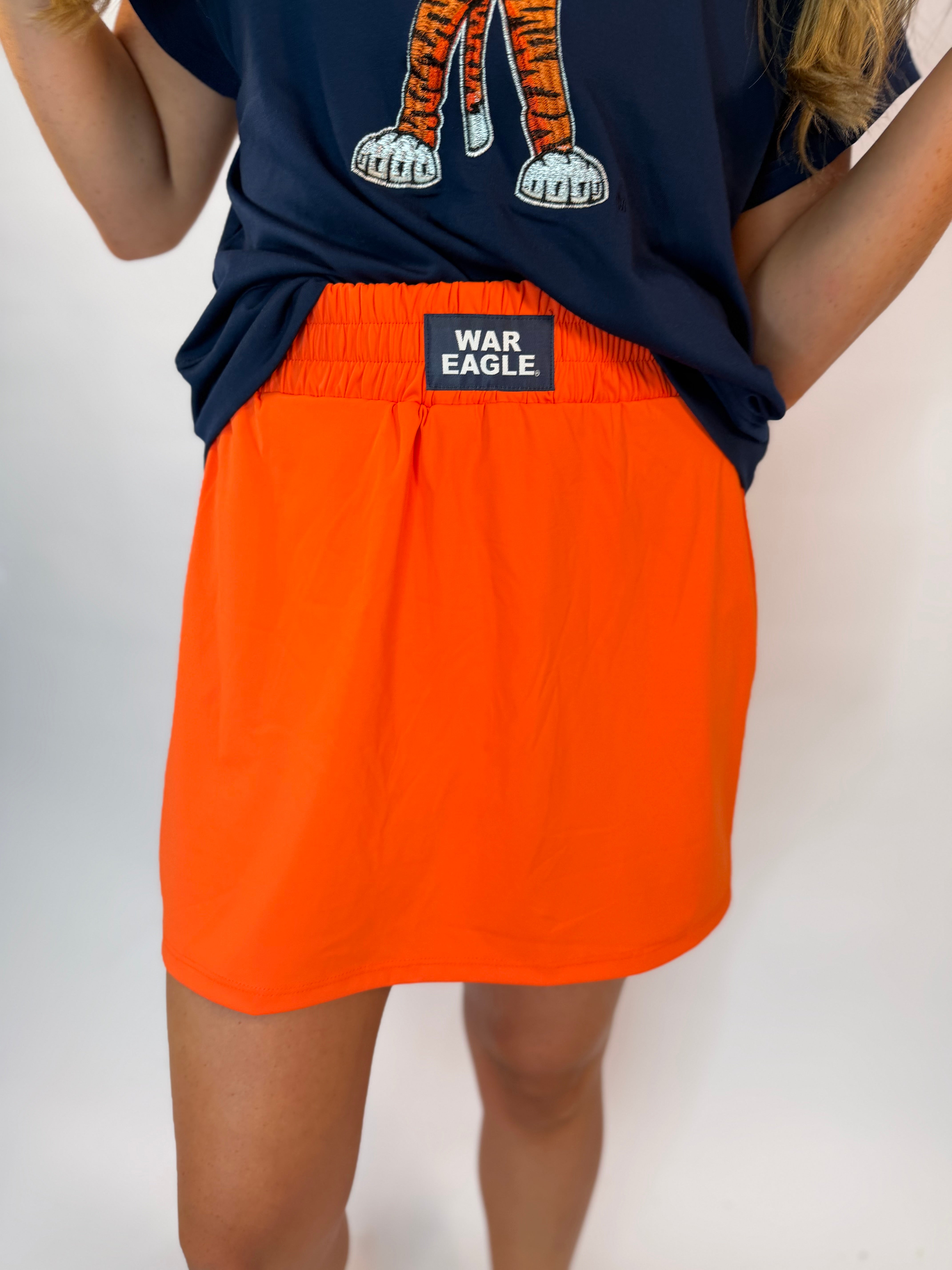 Orange high-waisted skort with navy "War Eagle" label, paired with navy Auburn tiger graphic tee.