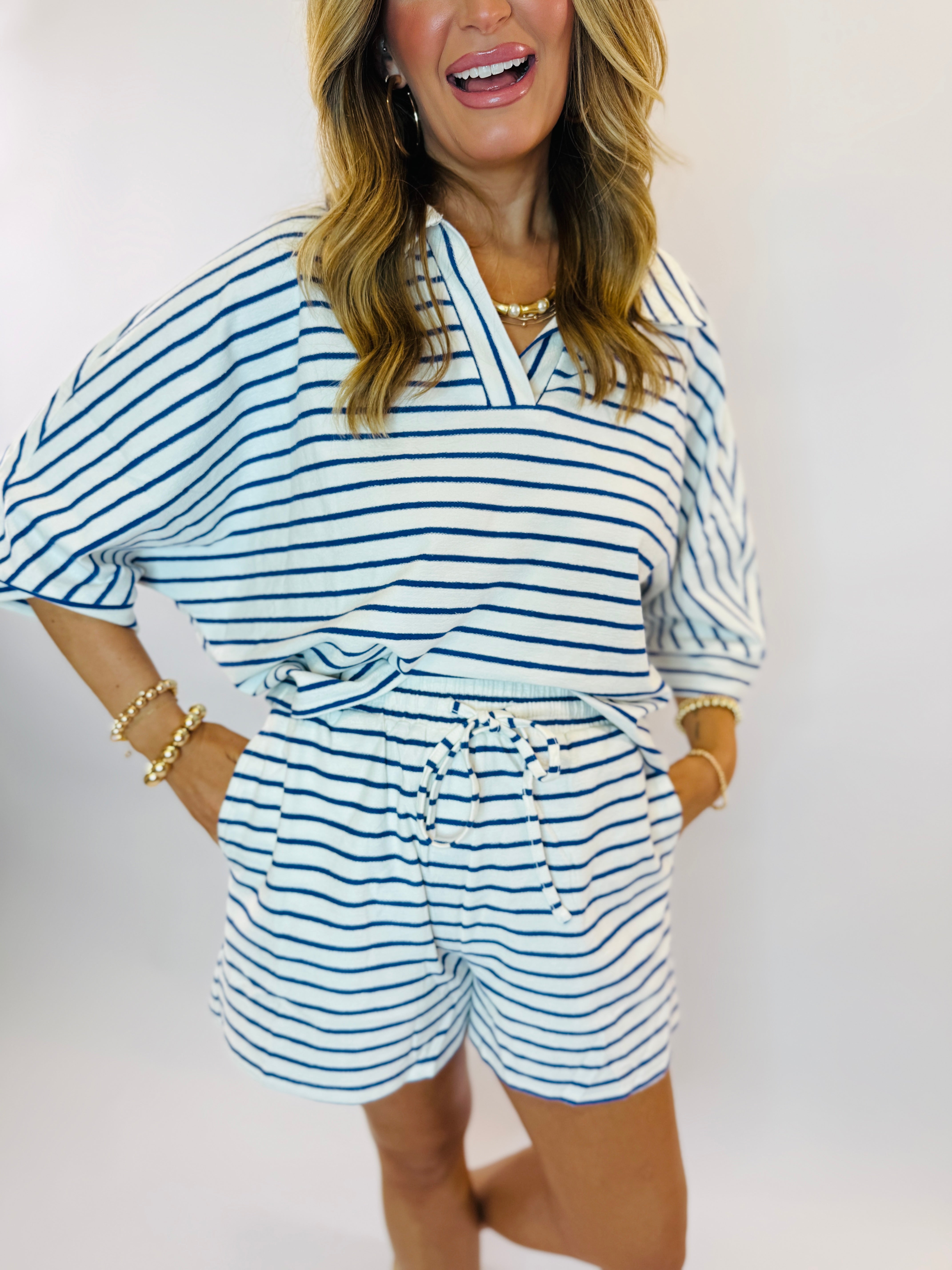 Woman wearing blue and white striped loungewear set with drawstring shorts and V-neck top.