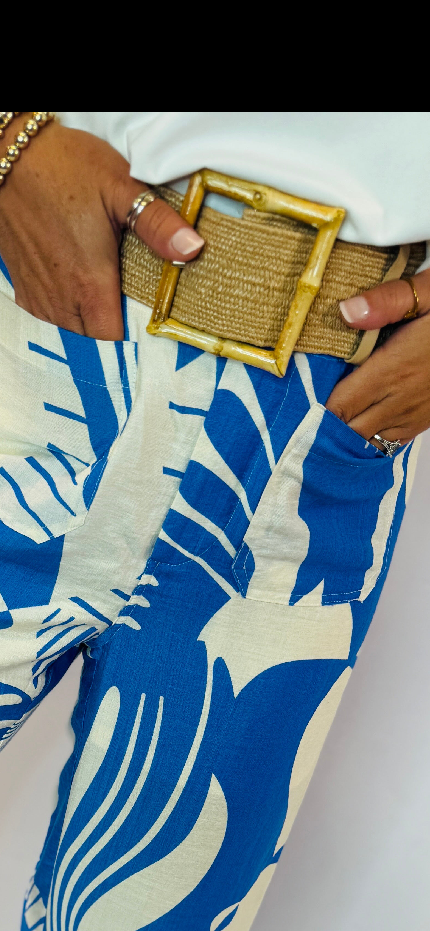 Khaki woven belt with gold square buckle worn with blue and white patterned dress
