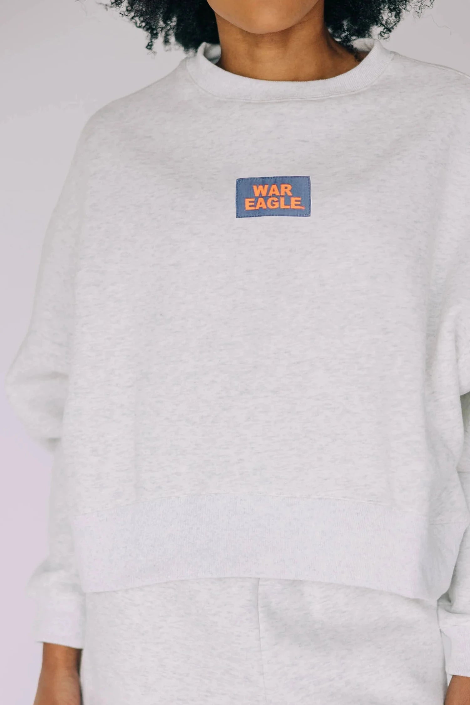 Light gray oversized crewneck sweatshirt with navy and orange "War Eagle" woven label patch.