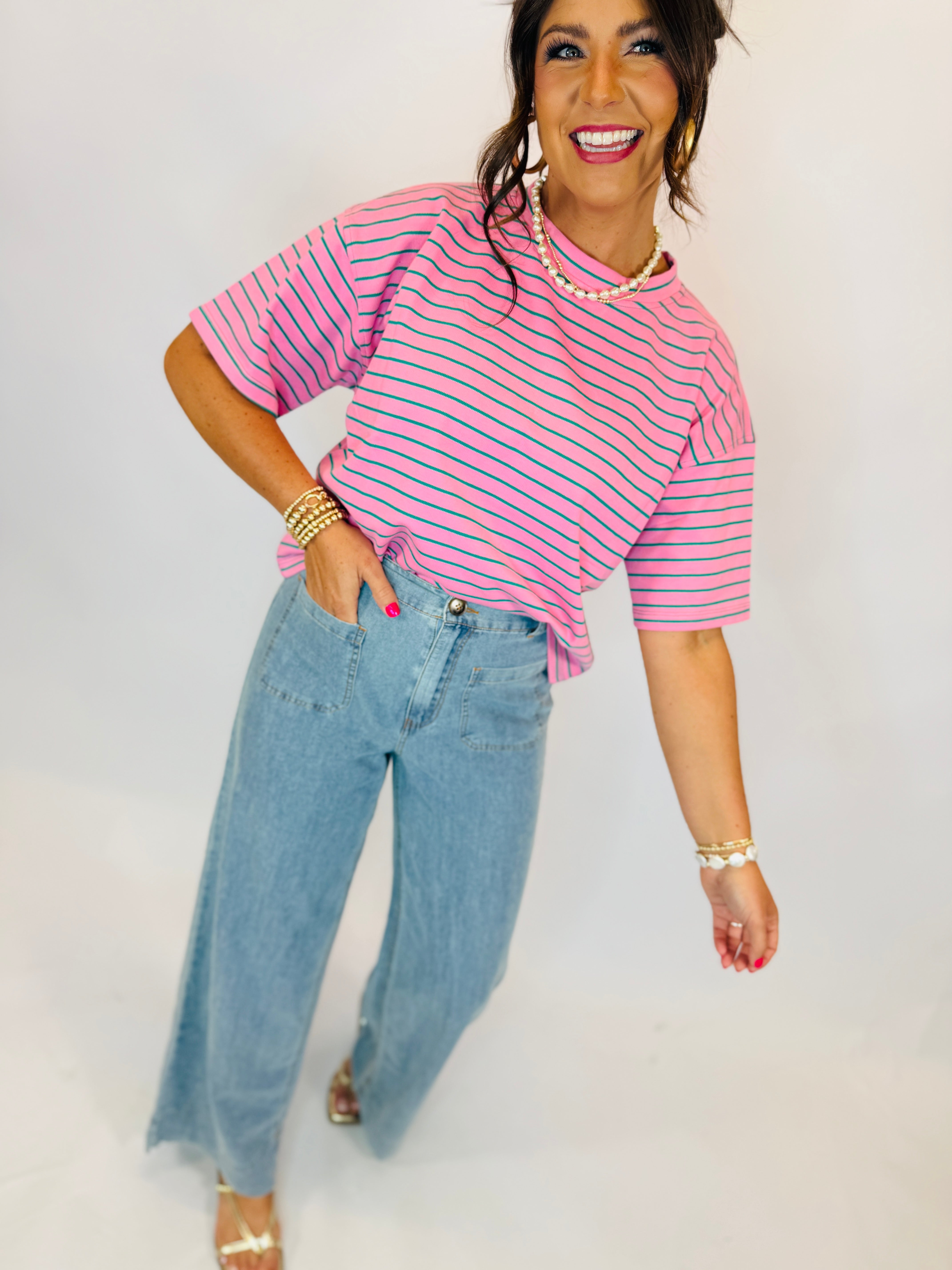 Woman wearing pink and green striped short-sleeve Taylor Top with light wash wide-leg jeans.