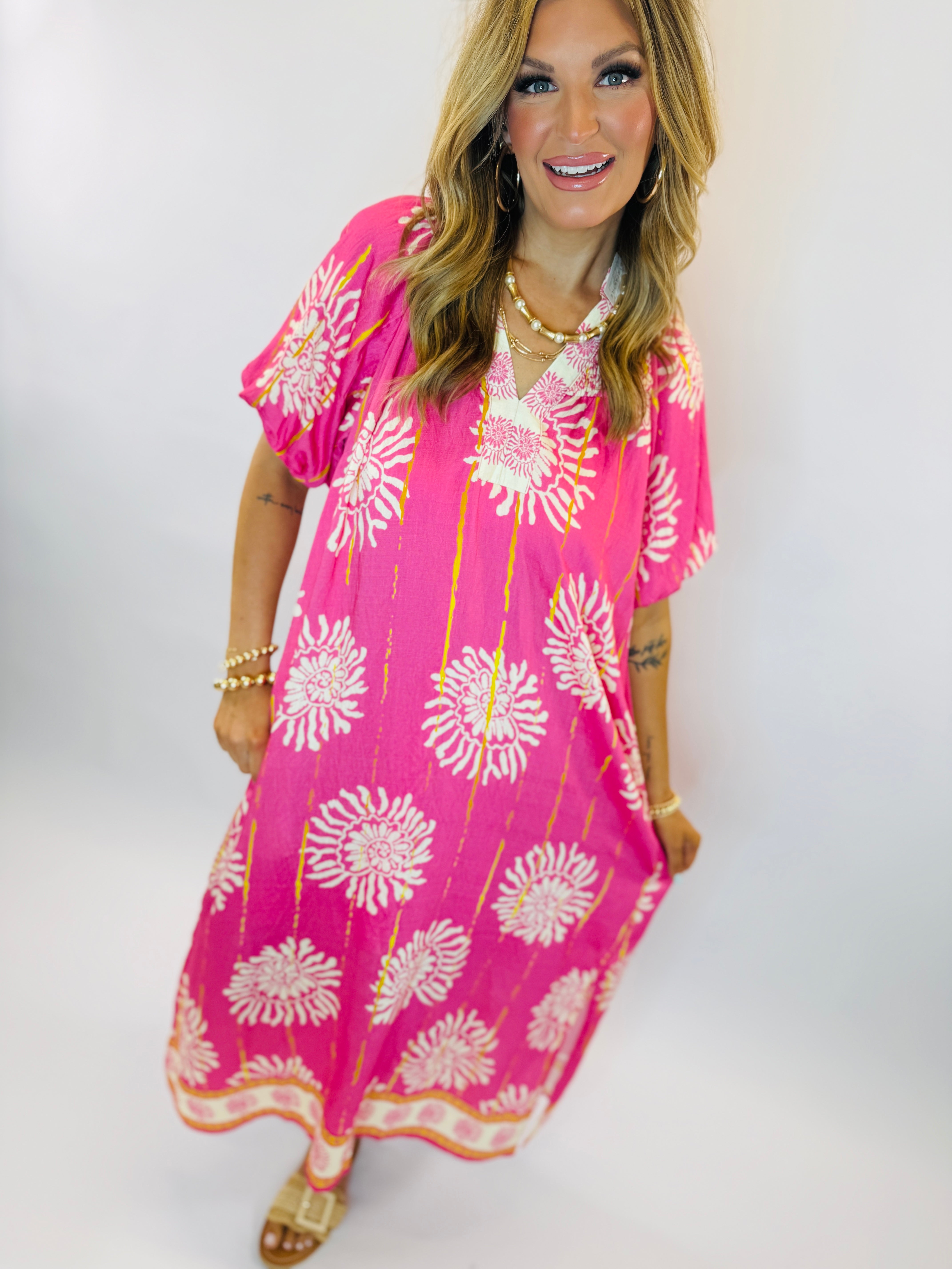Woman wearing bright pink floral print Chloe Maxi dress with white sunburst pattern and flowing sleeves