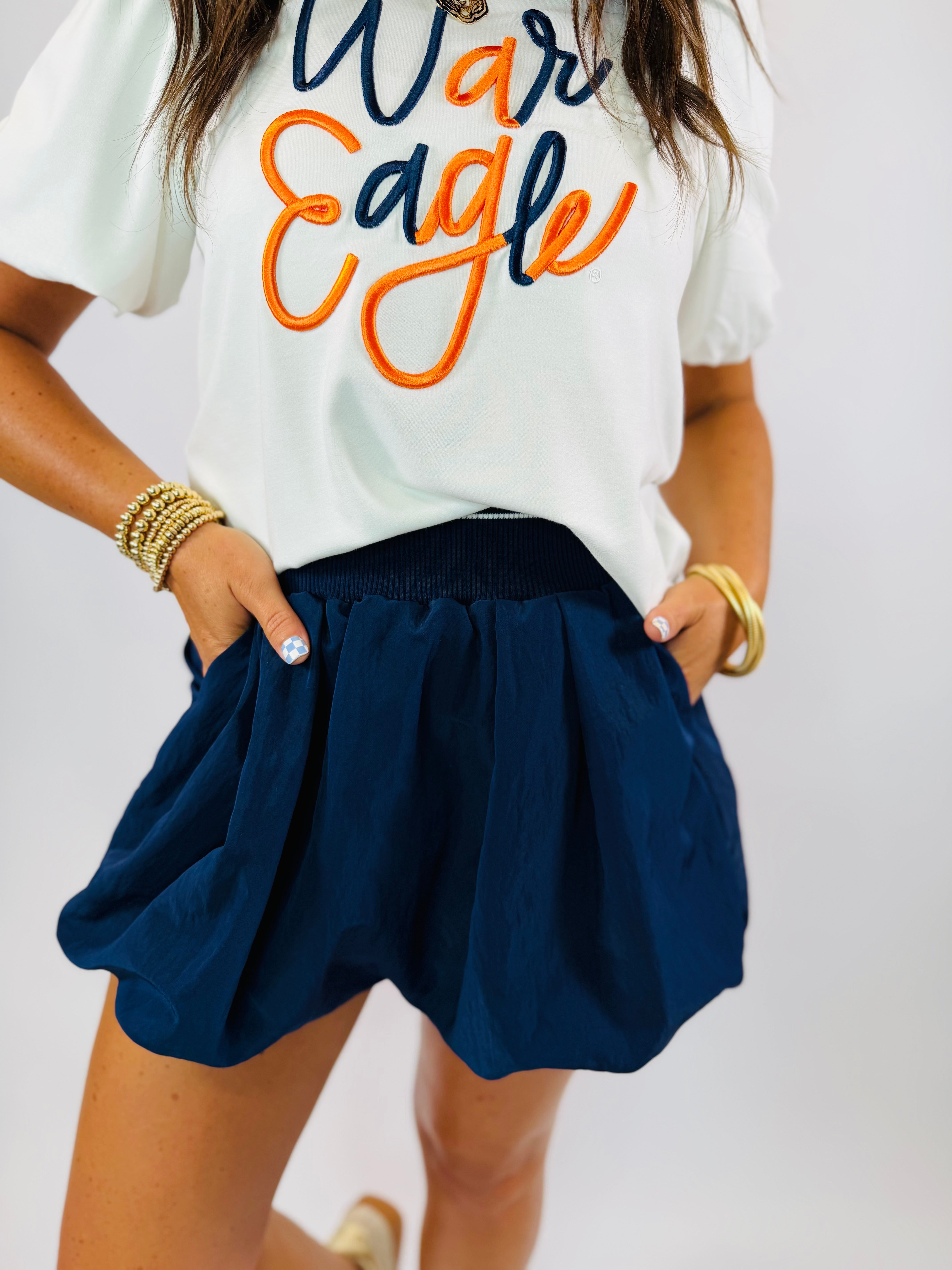 Navy blue bubble skort with elastic waistband and pockets, paired with a white War Eagle graphic tee.