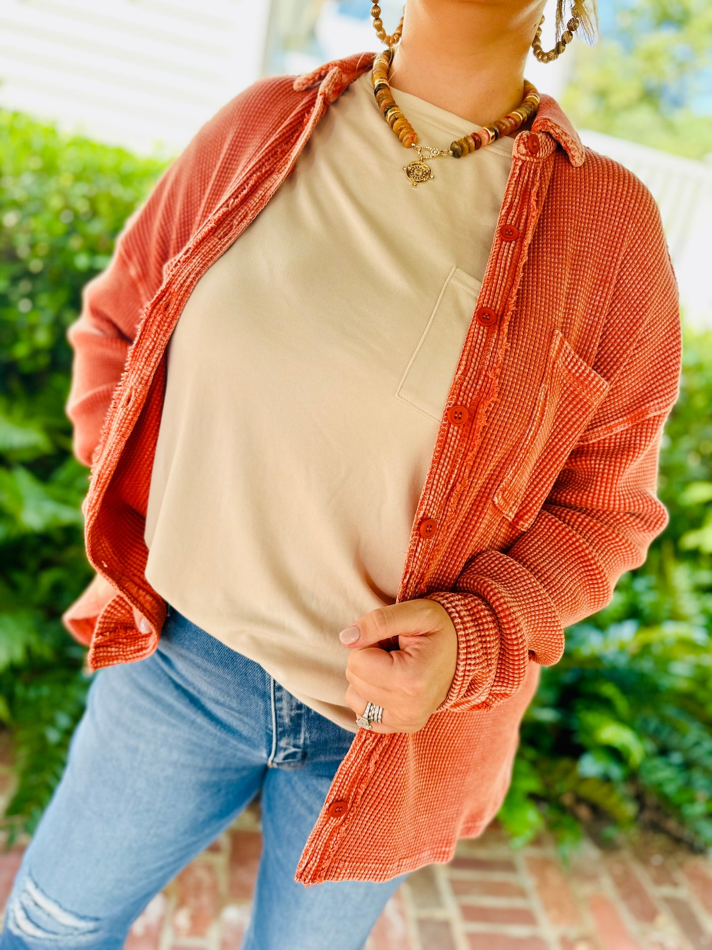 Woman wearing beige Tatum pocket top with coral textured cardigan and layered beaded necklaces