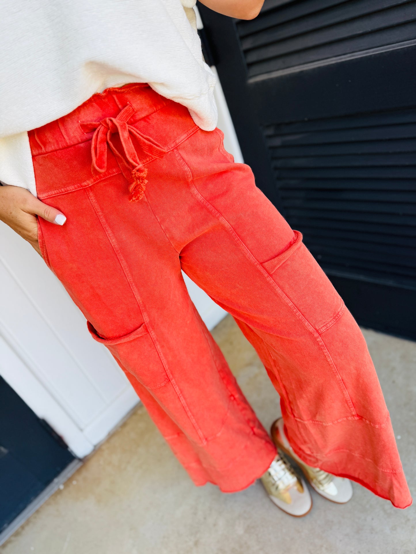 Bright red cargo pants with drawstring waist and side pockets, styled with white top and sneakers.