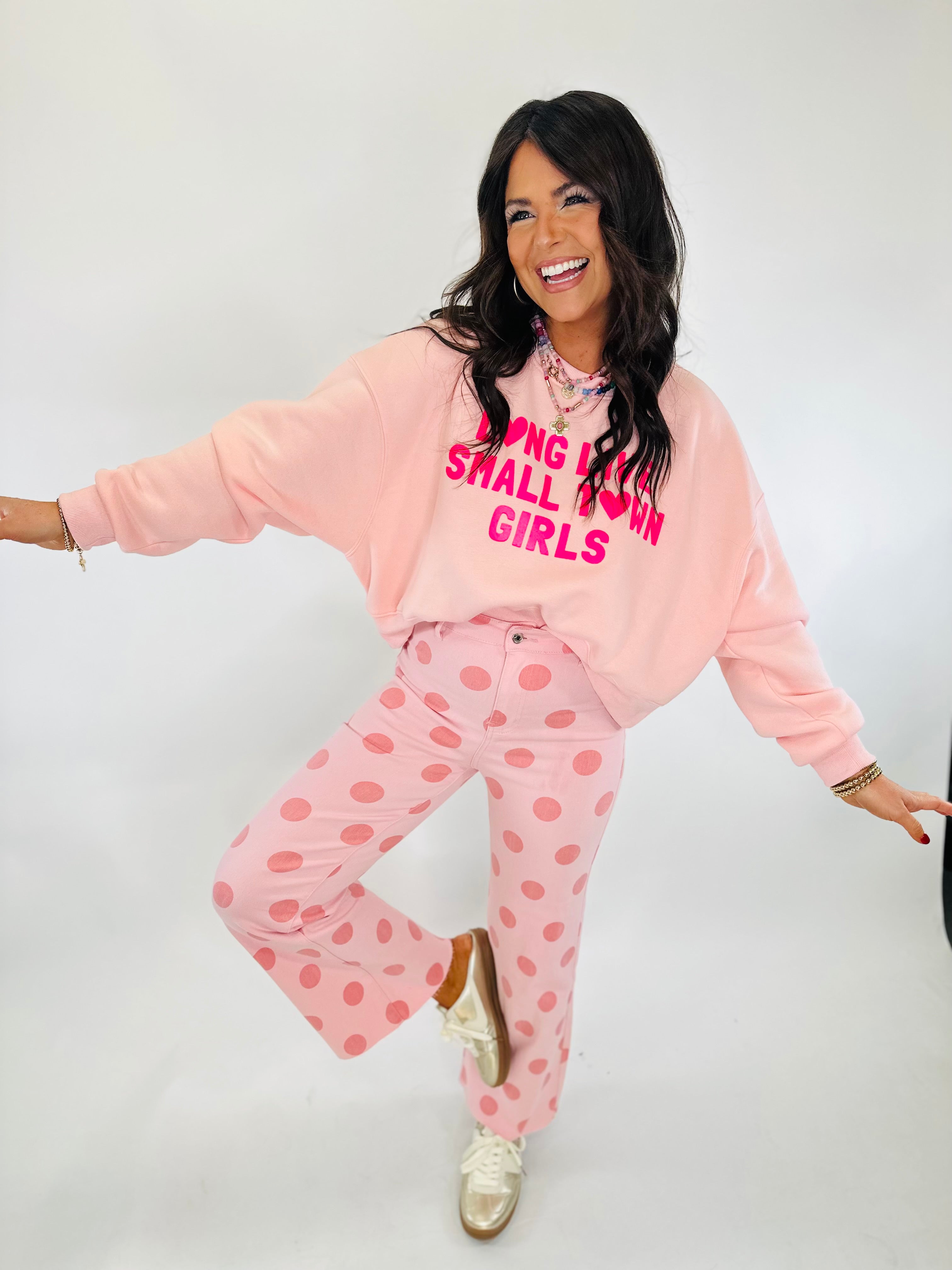 Woman wearing pink oversized sweatshirt with "LONG LIVE SMALL TOWN GIRLS" text and pink polka dot pants