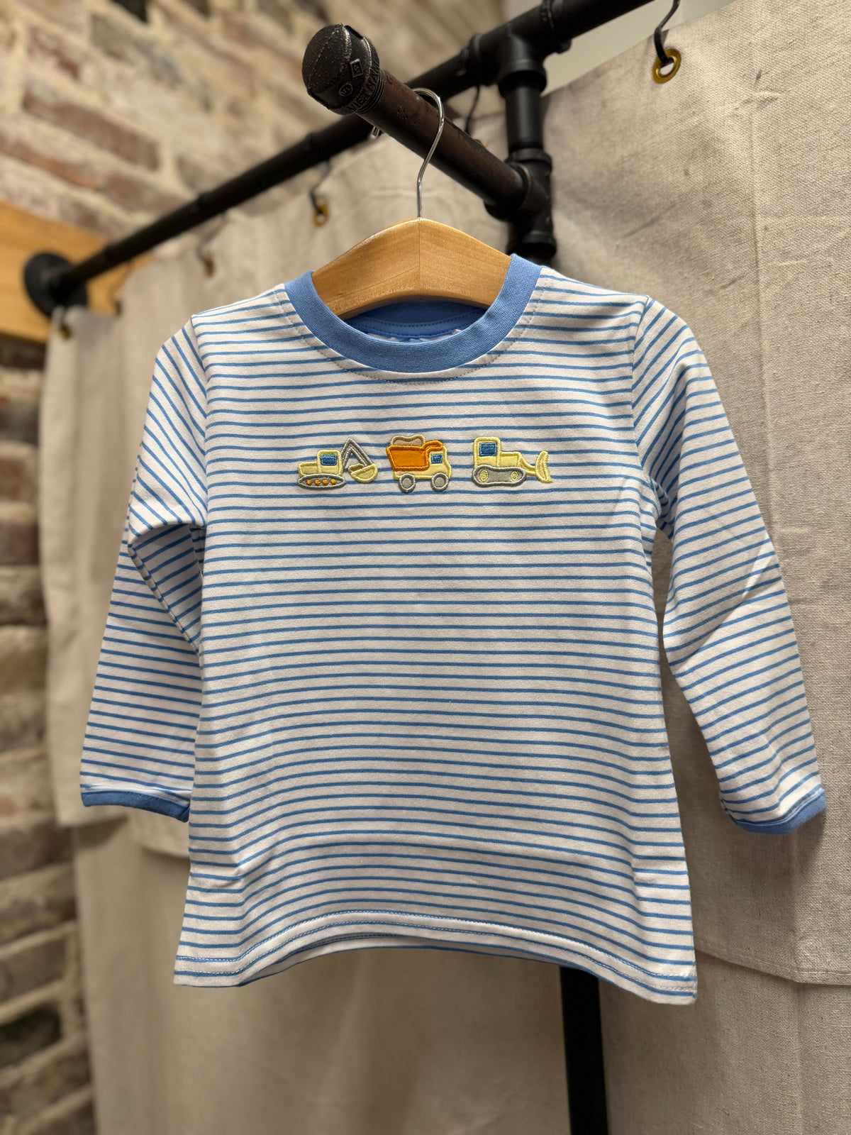 Children's long-sleeve blue and white striped shirt with embroidered construction truck appliqués on chest.