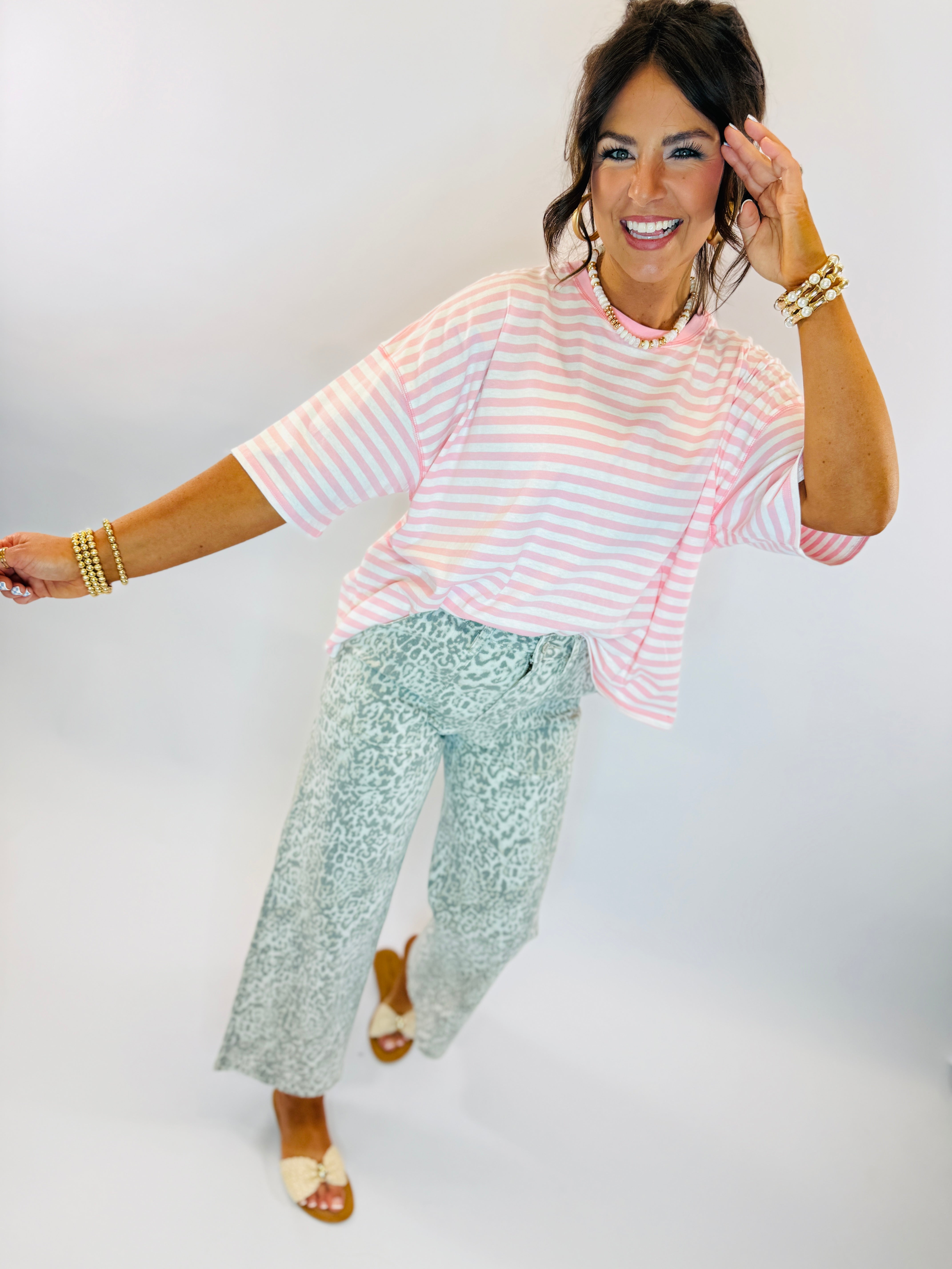 Woman wearing pink striped top and light blue leopard print wide-leg Vickie printed denim jeans with sandals.