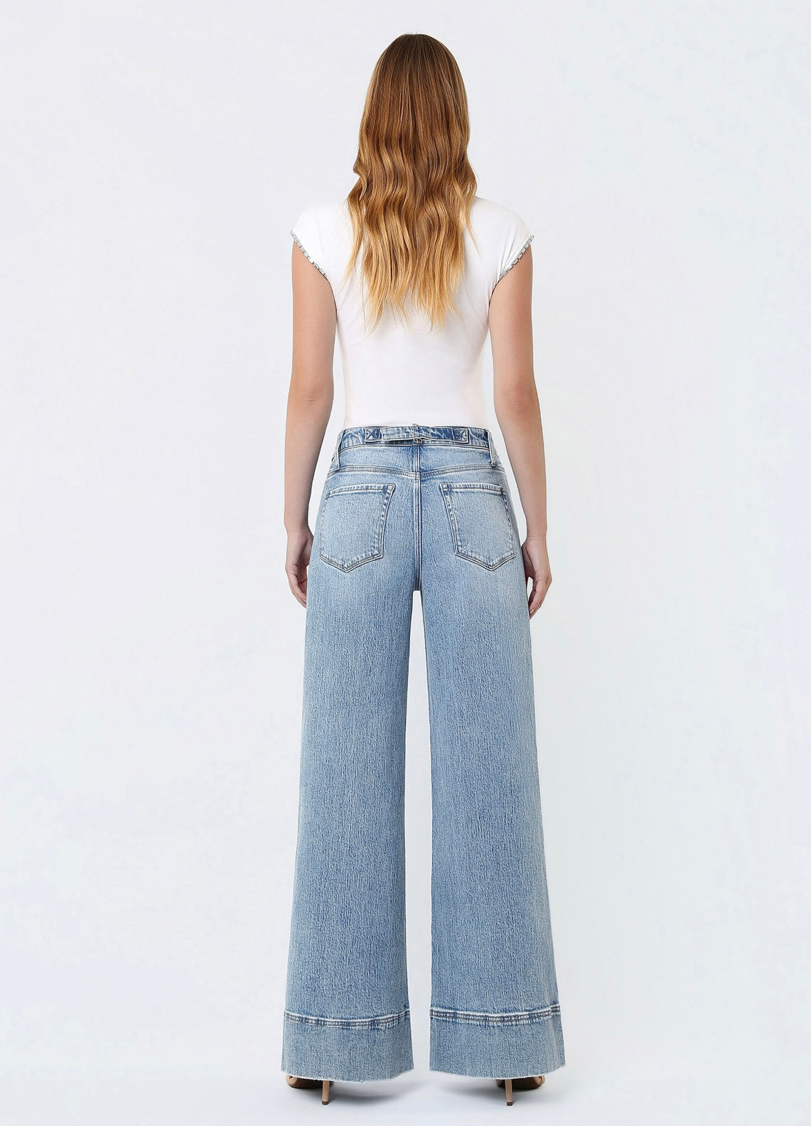 Back view of woman wearing white top and light blue wide-leg denim jeans with cuffed hems