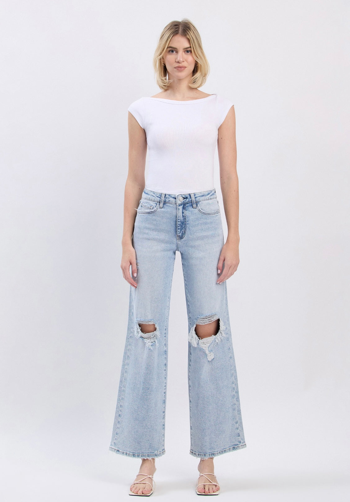 Woman wearing white top and light blue distressed wide-leg Josephine denim pants with knee rips