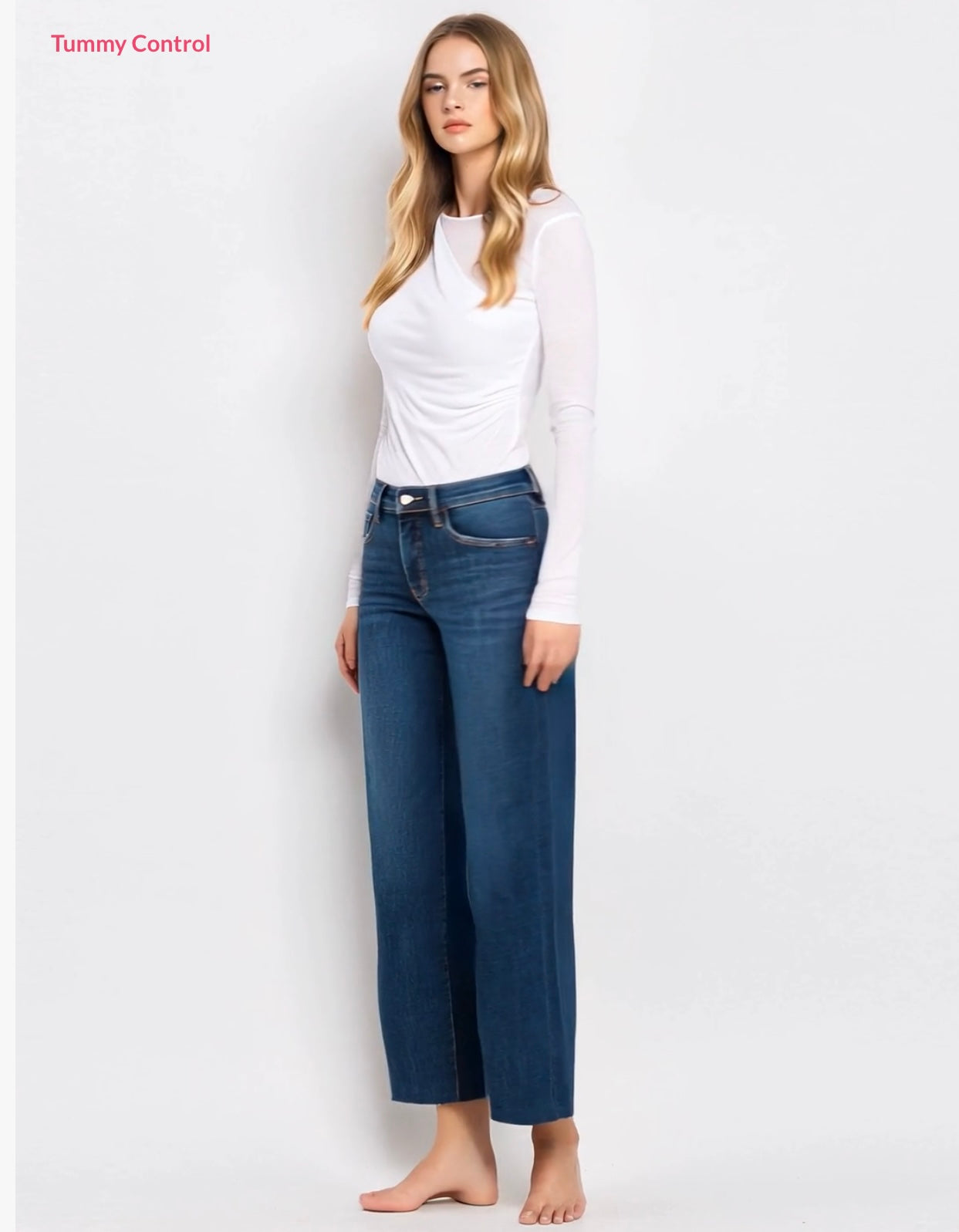 Woman wearing white long-sleeve top and blue wide leg cropped jeans with tummy control feature.