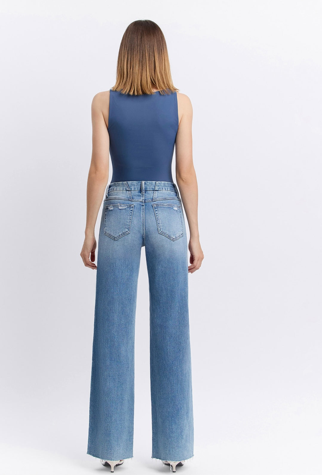 Woman wearing blue tank top and light wash wide-leg Natalie denim pants, shown from behind.