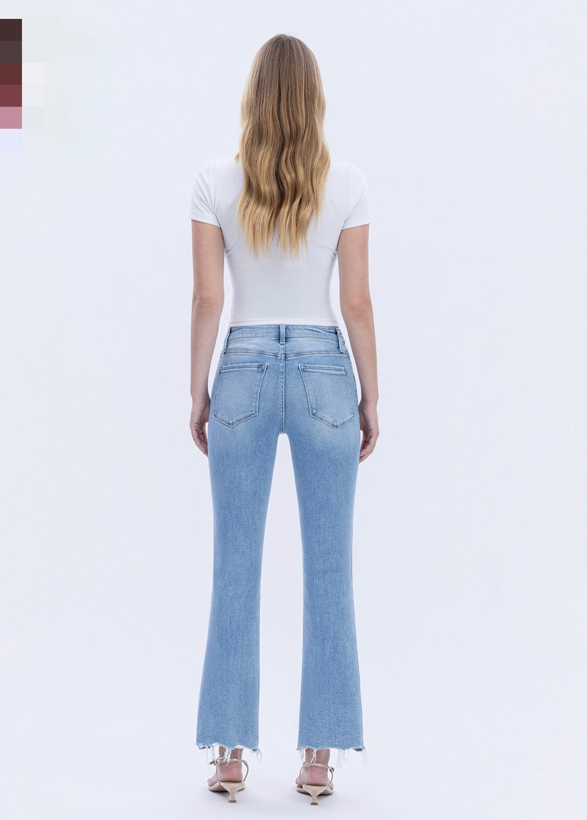 Woman wearing light blue flare jeans with frayed hem and white t-shirt, shown from behind